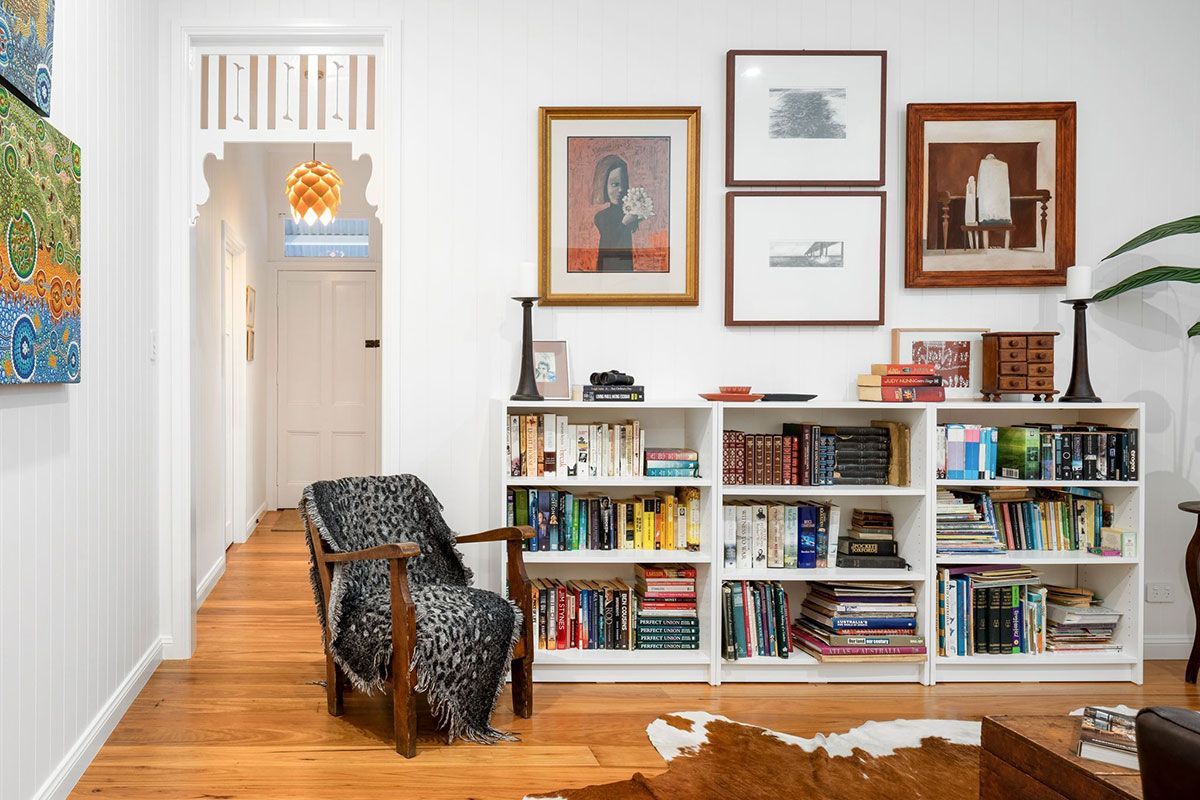 a living room with a bookshelf filled with books and a chair .