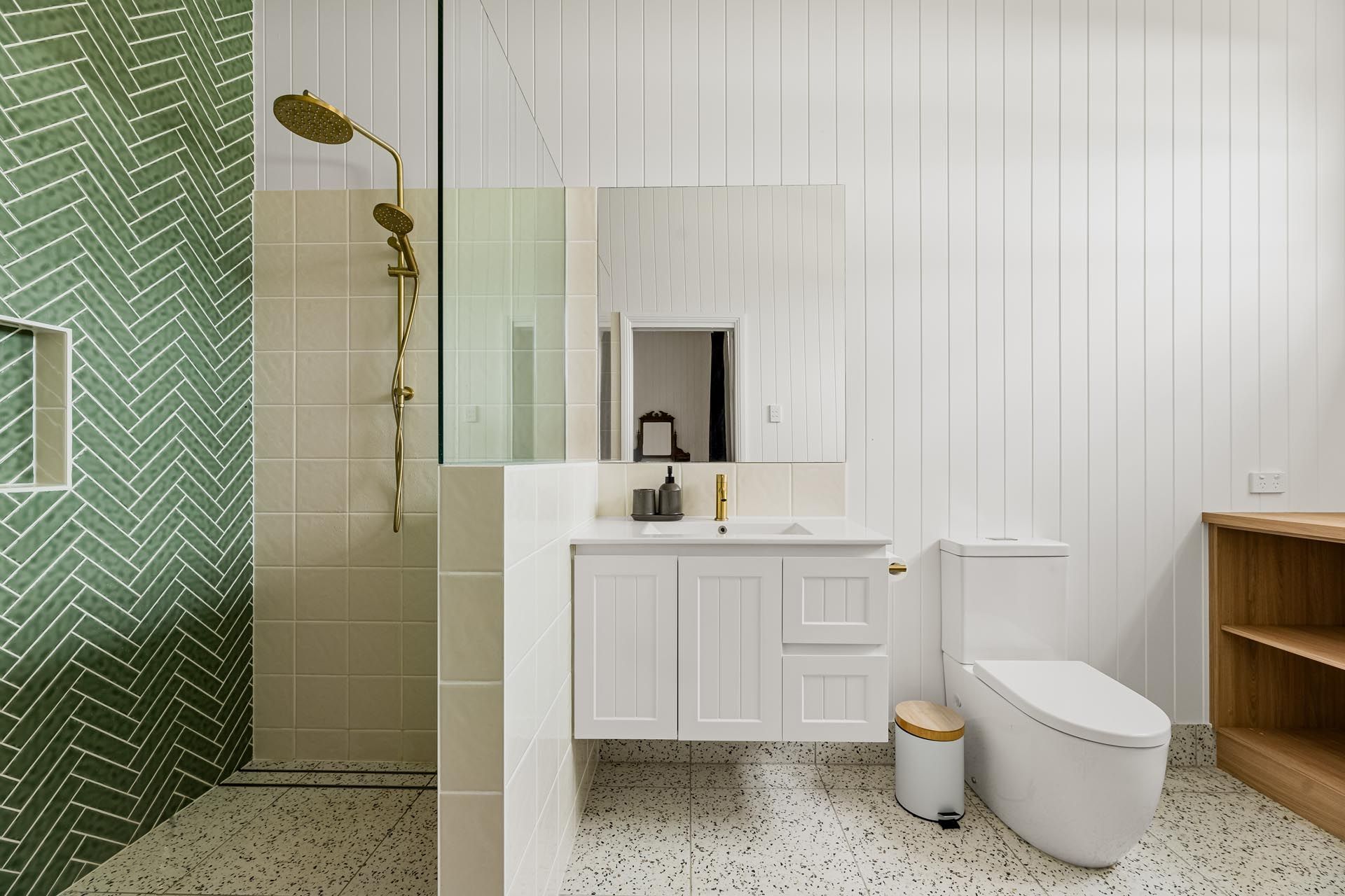 A bathroom with a toilet , sink , shower and green tiles.
