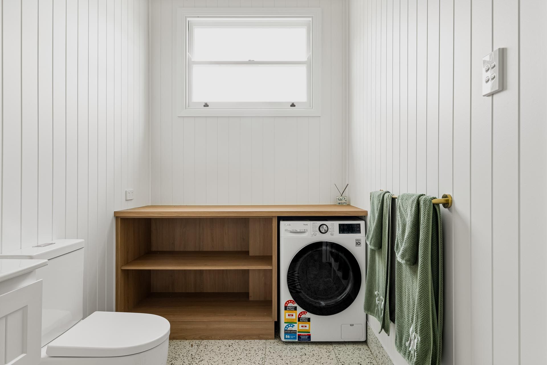 A bathroom with a toilet , washer and dryer.