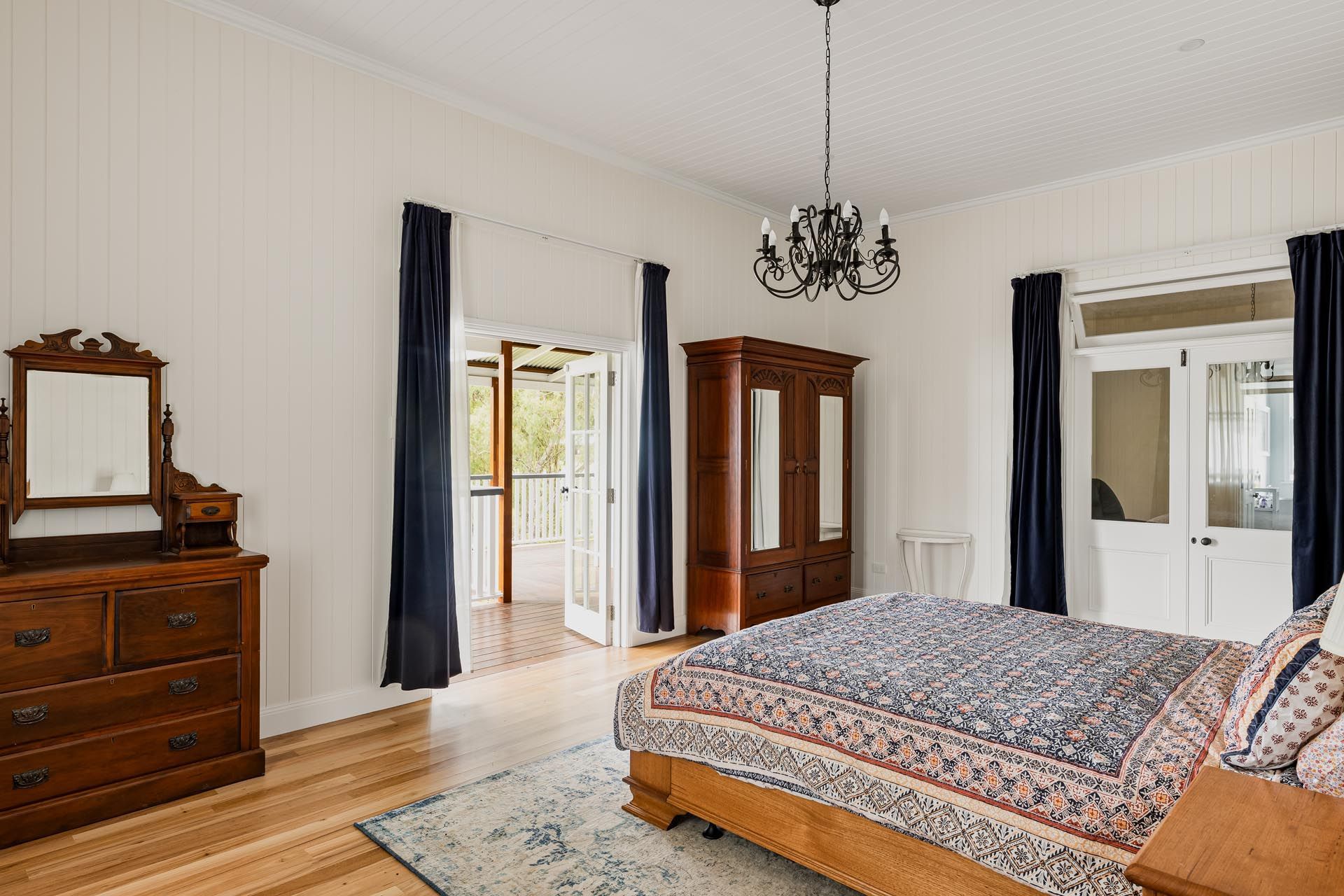 A bedroom with a bed , dresser , mirror and chandelier.