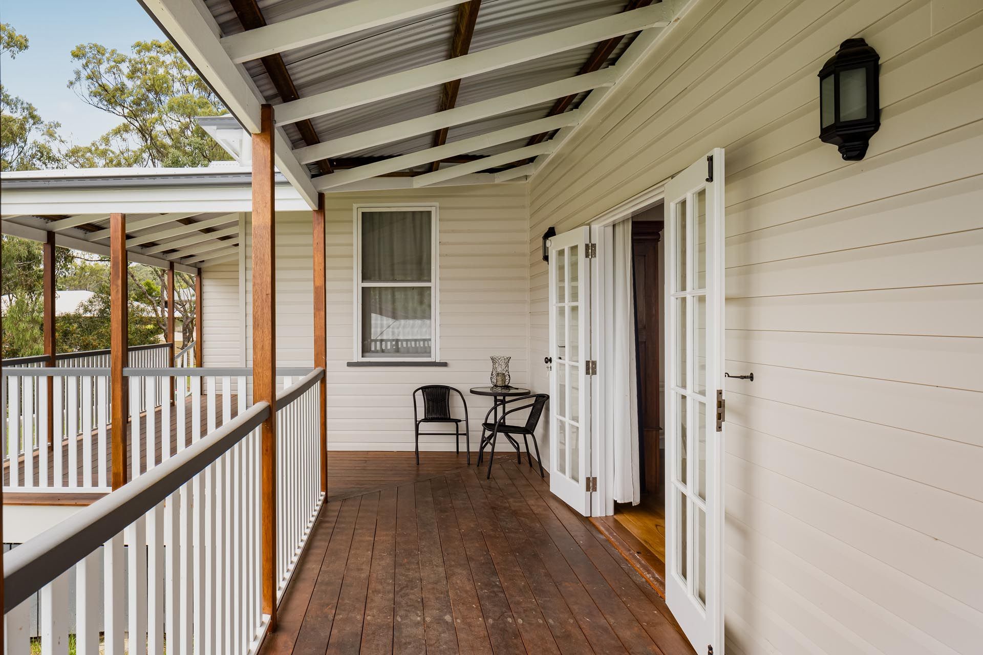 A white house with a wooden deck and a table and chairs on it.