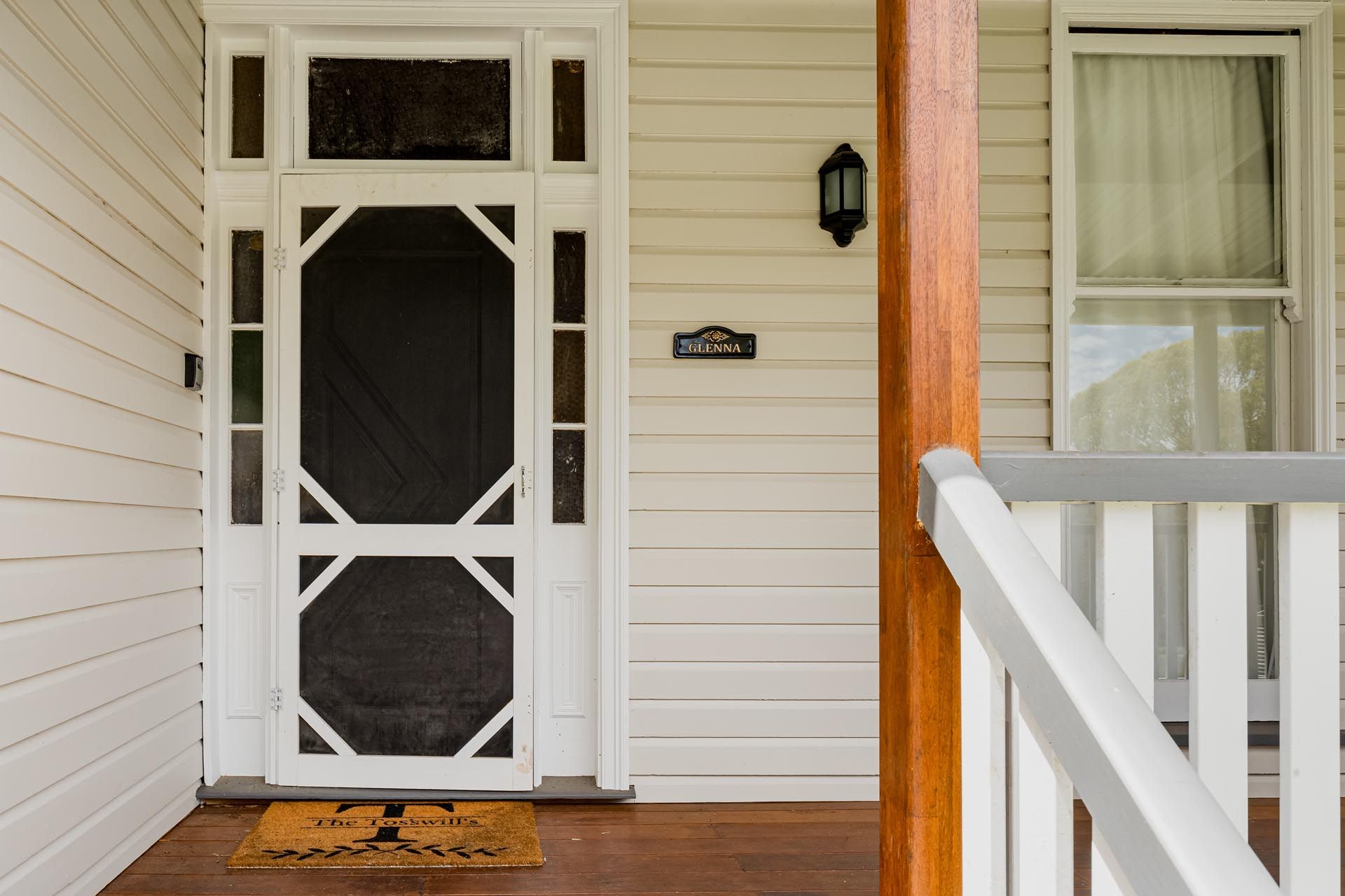 The front door of a white house with a screen door