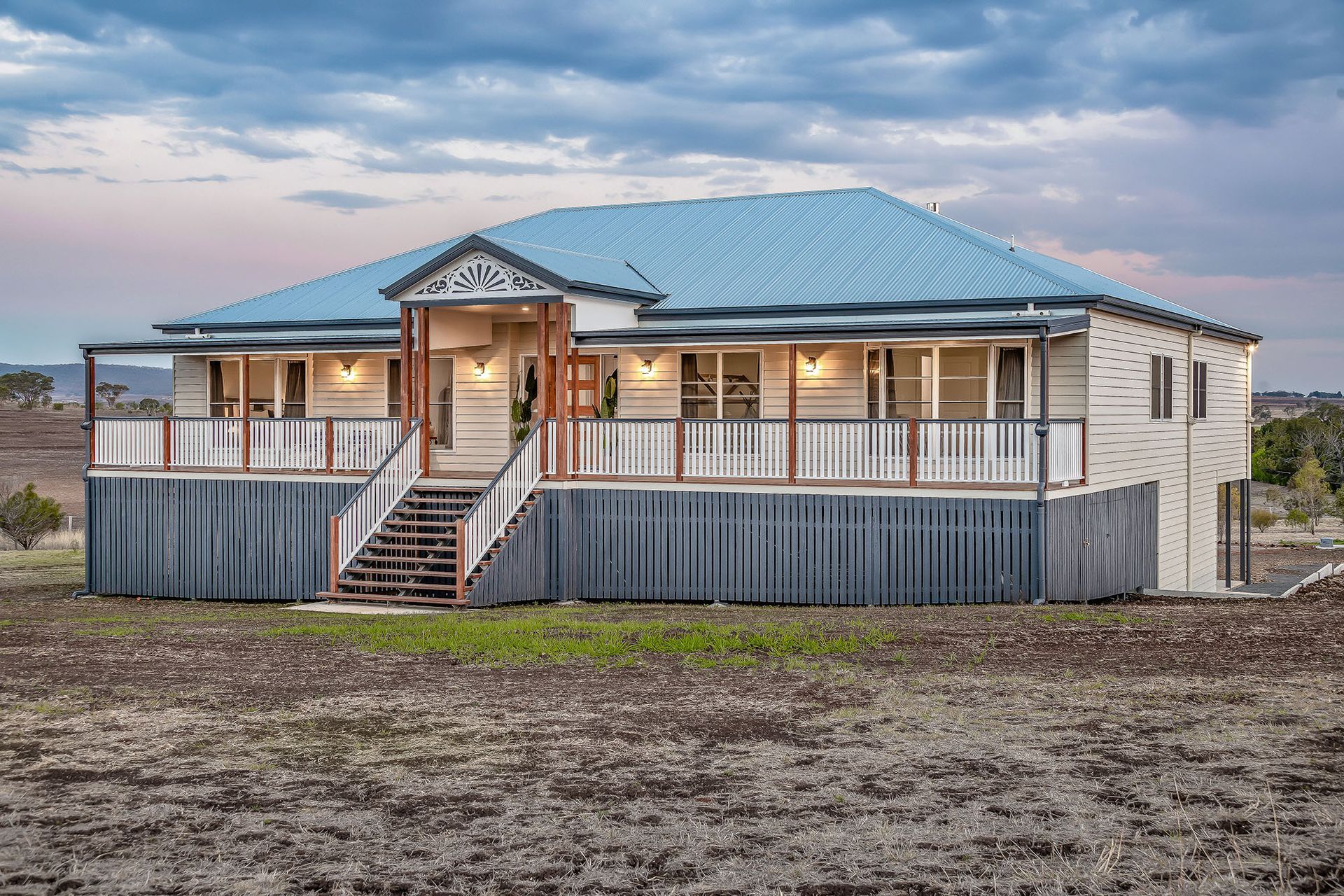 a large house with a blue roof is sitting in the middle of a dirt field .