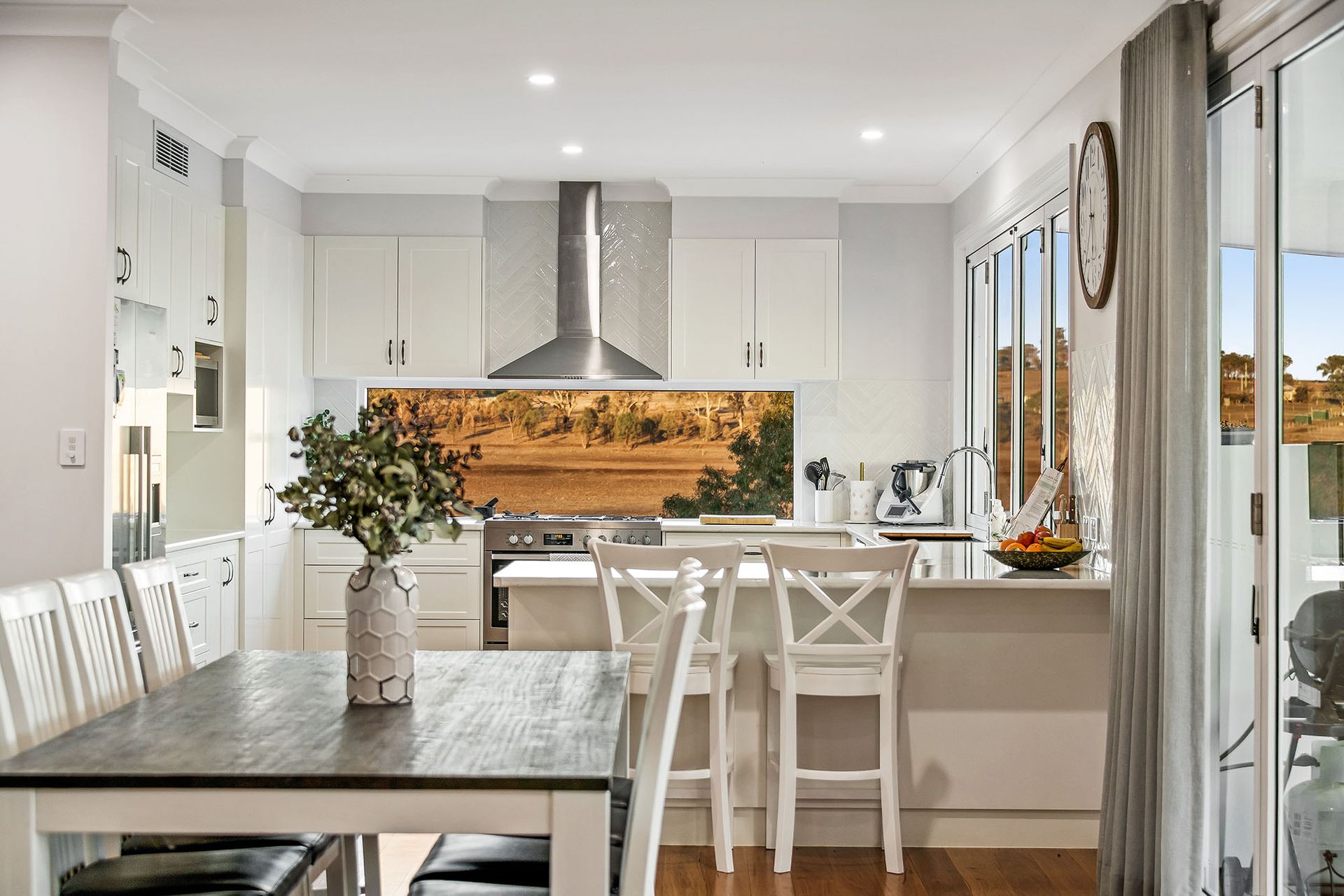a kitchen with a table and chairs and a vase of flowers on the table .