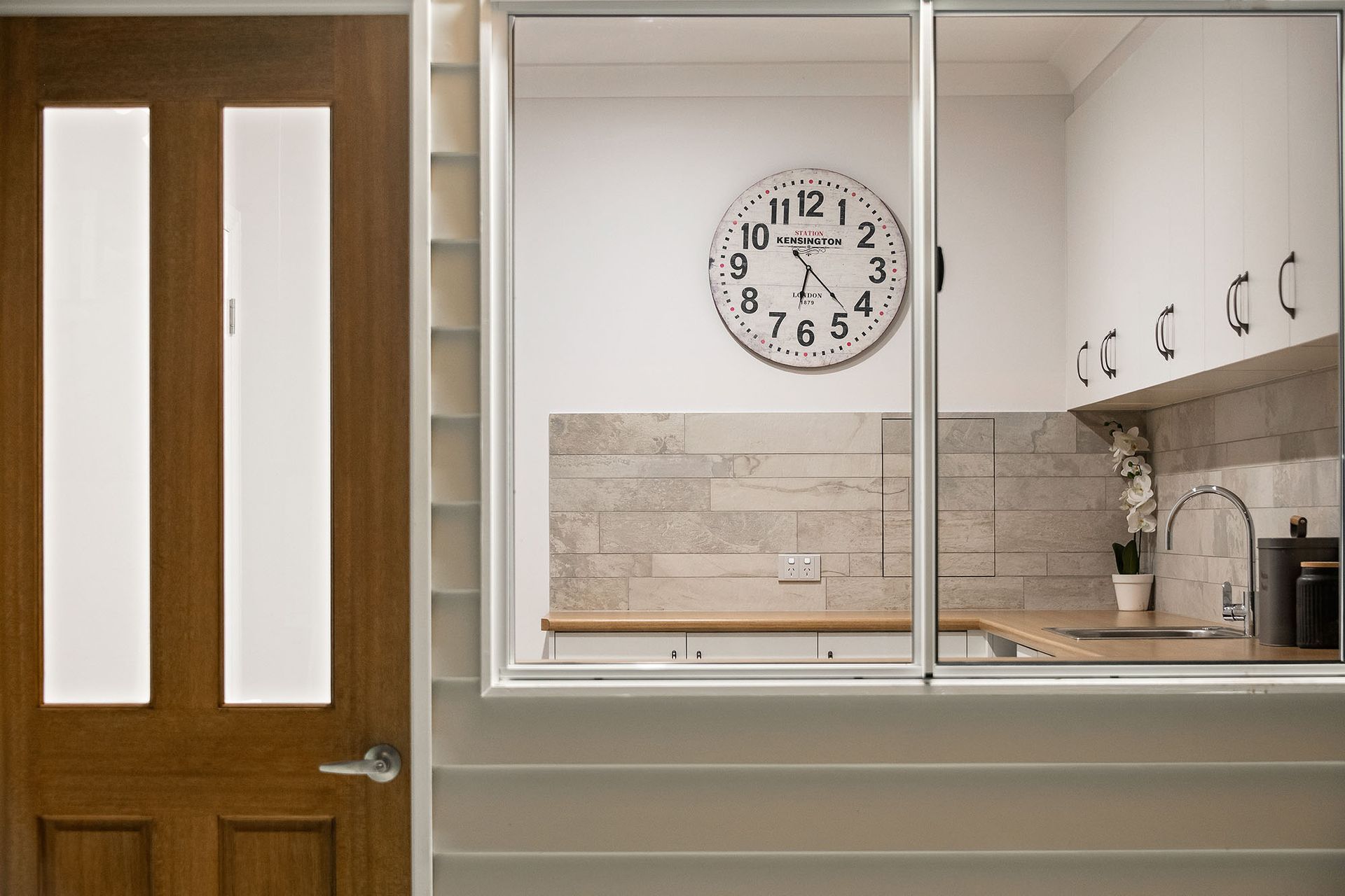 a kitchen with a clock on the wall and a wooden door .