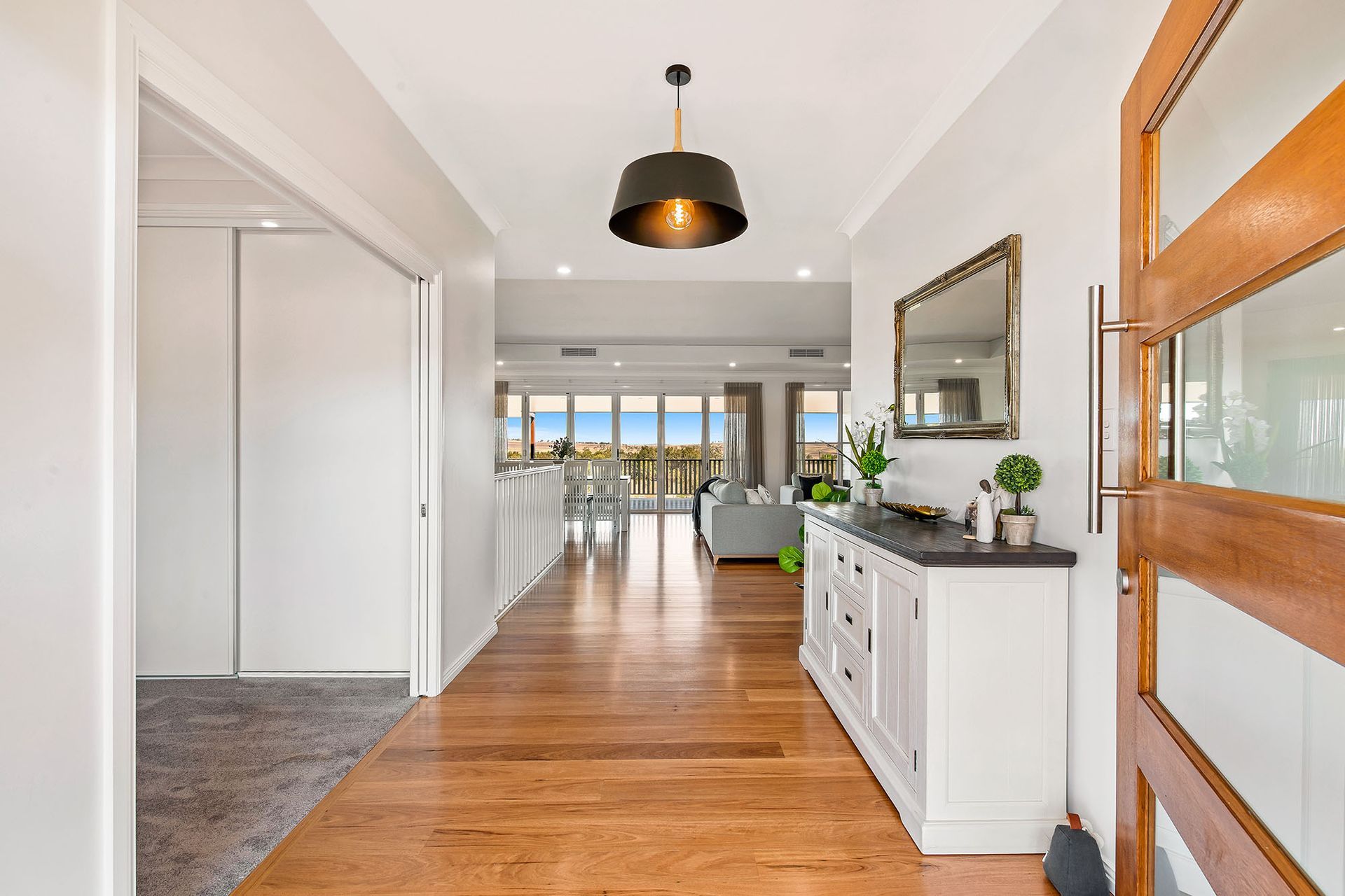 a hallway in a house with hardwood floors and a mirror .