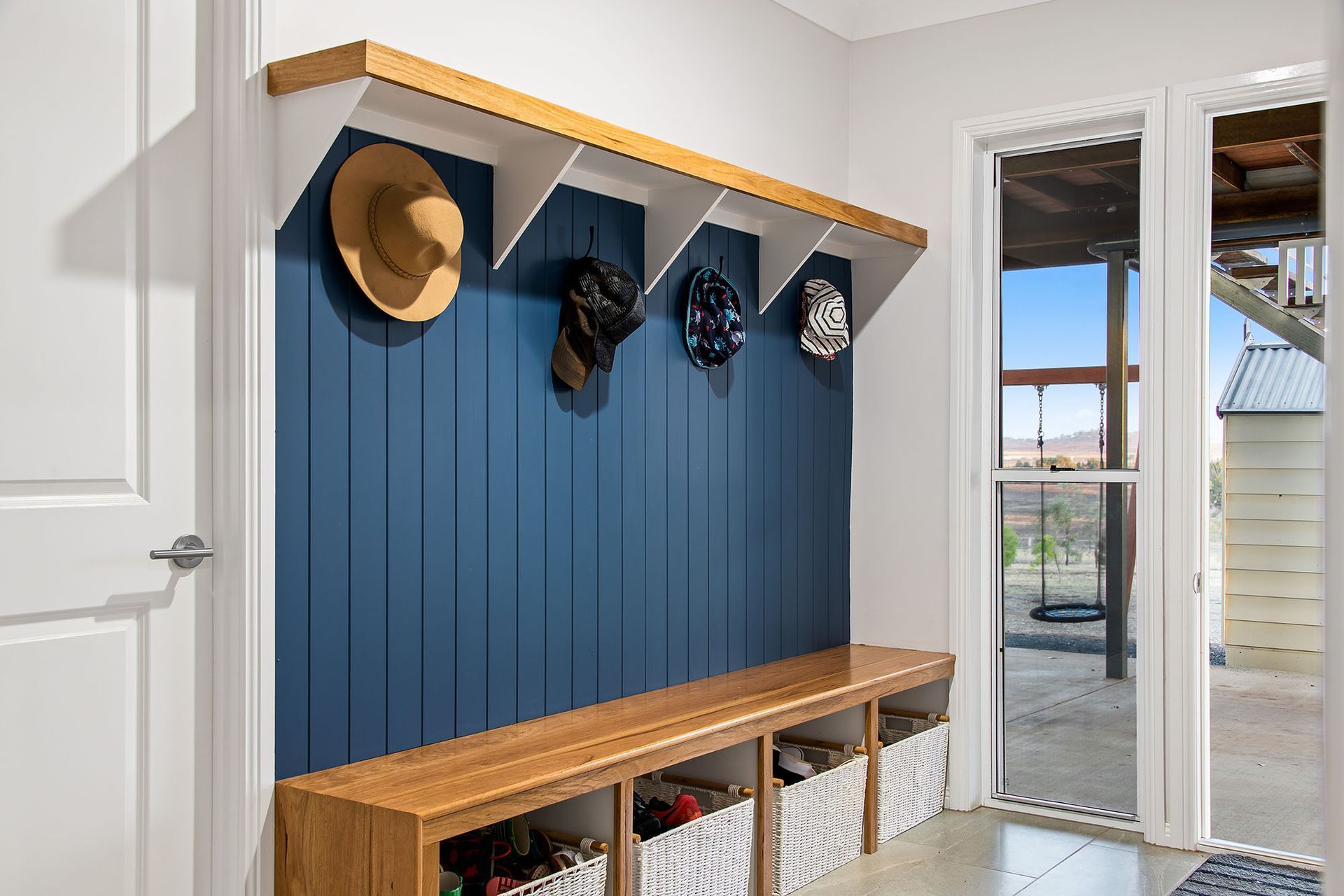 a hallway with a bench and a shelf with hats hanging on it .