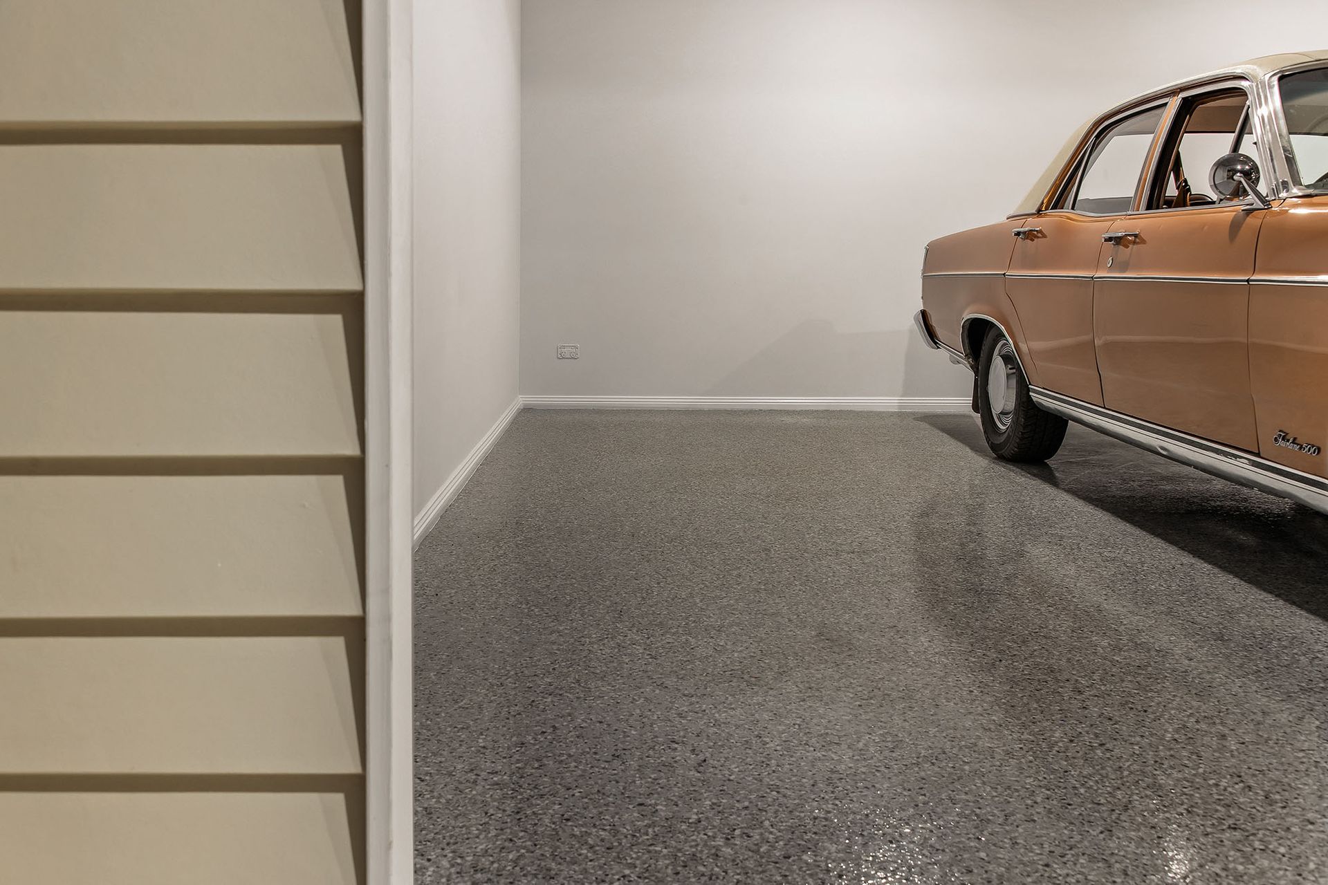 a car is parked in a garage next to a staircase .