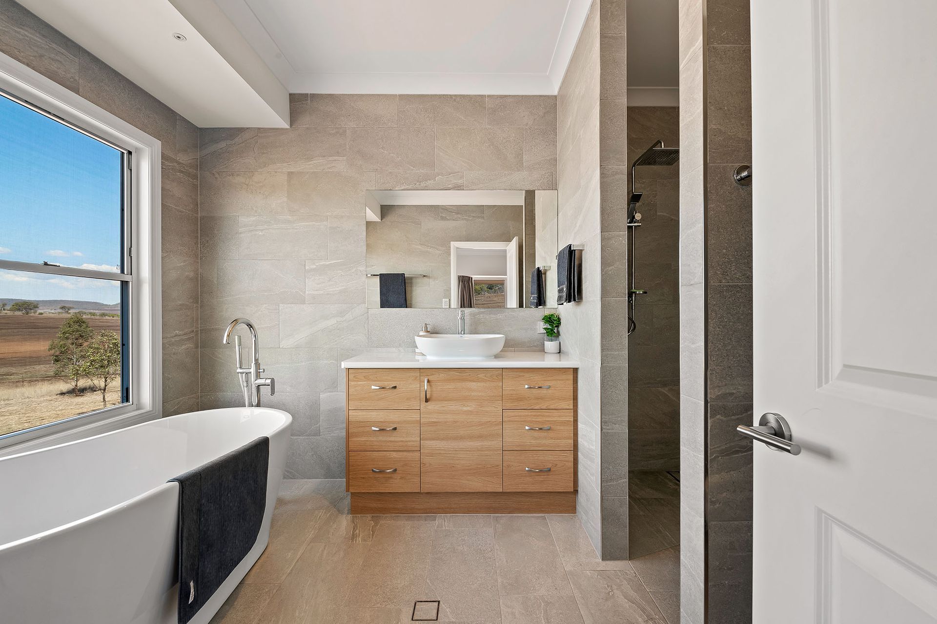 a bathroom with a tub , sink , mirror and window .