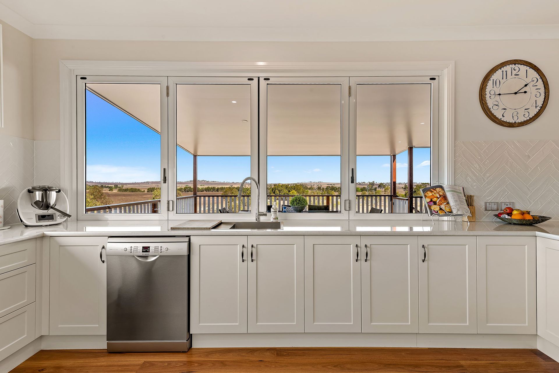 a kitchen with white cabinets , a dishwasher , and a clock on the wall .