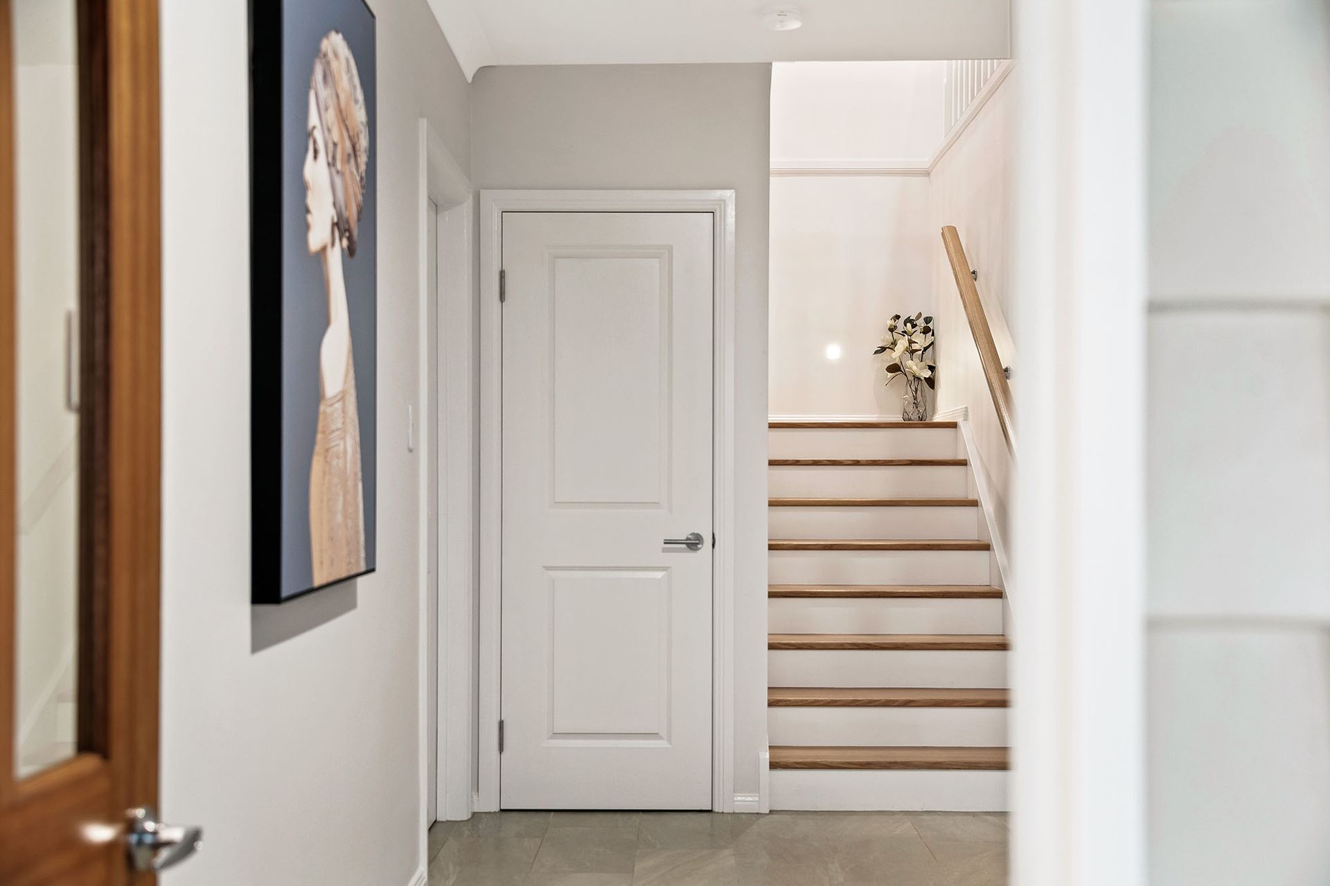 a hallway with stairs and a painting on the wall .