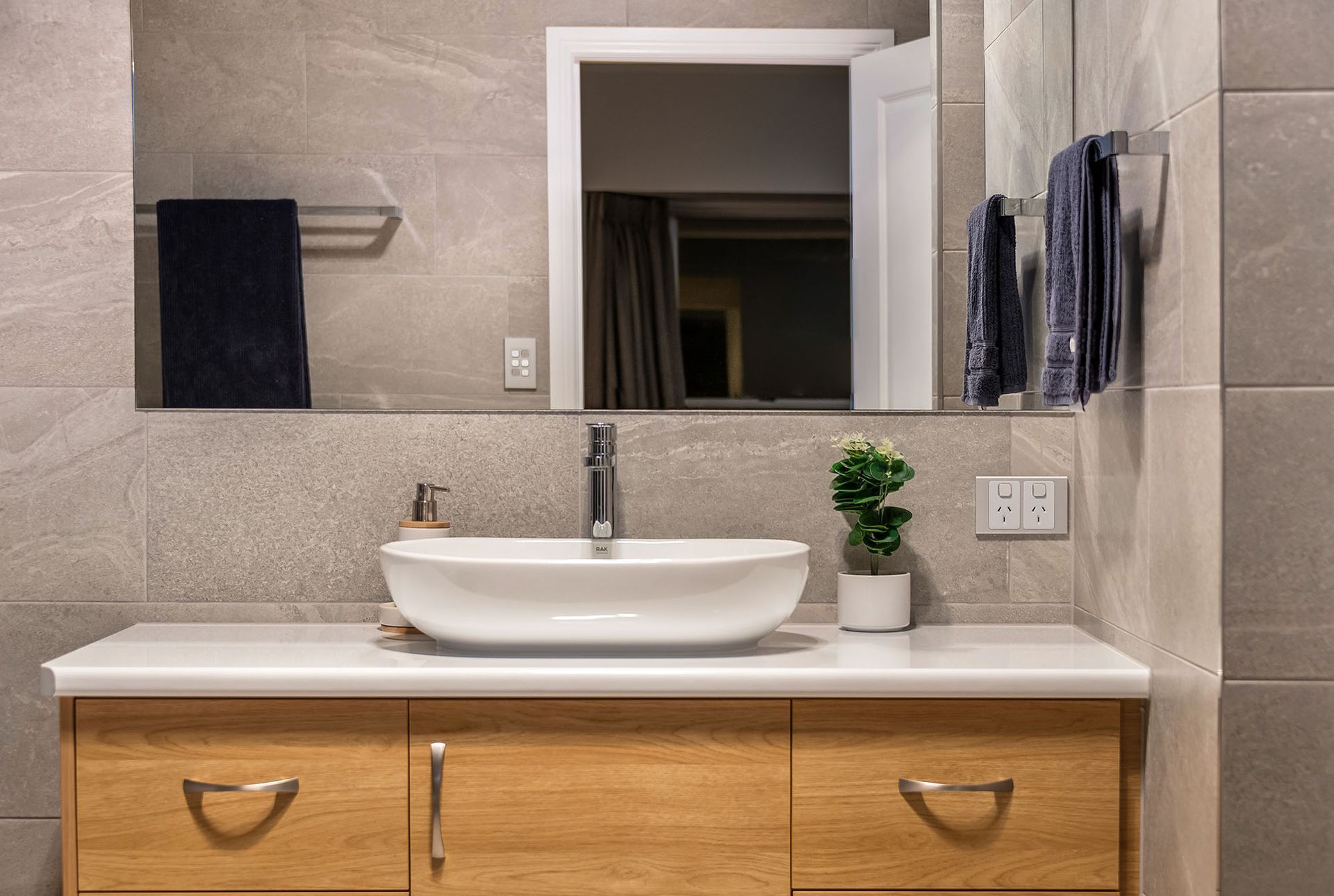 a bathroom with a sink , mirror , and wooden cabinets .