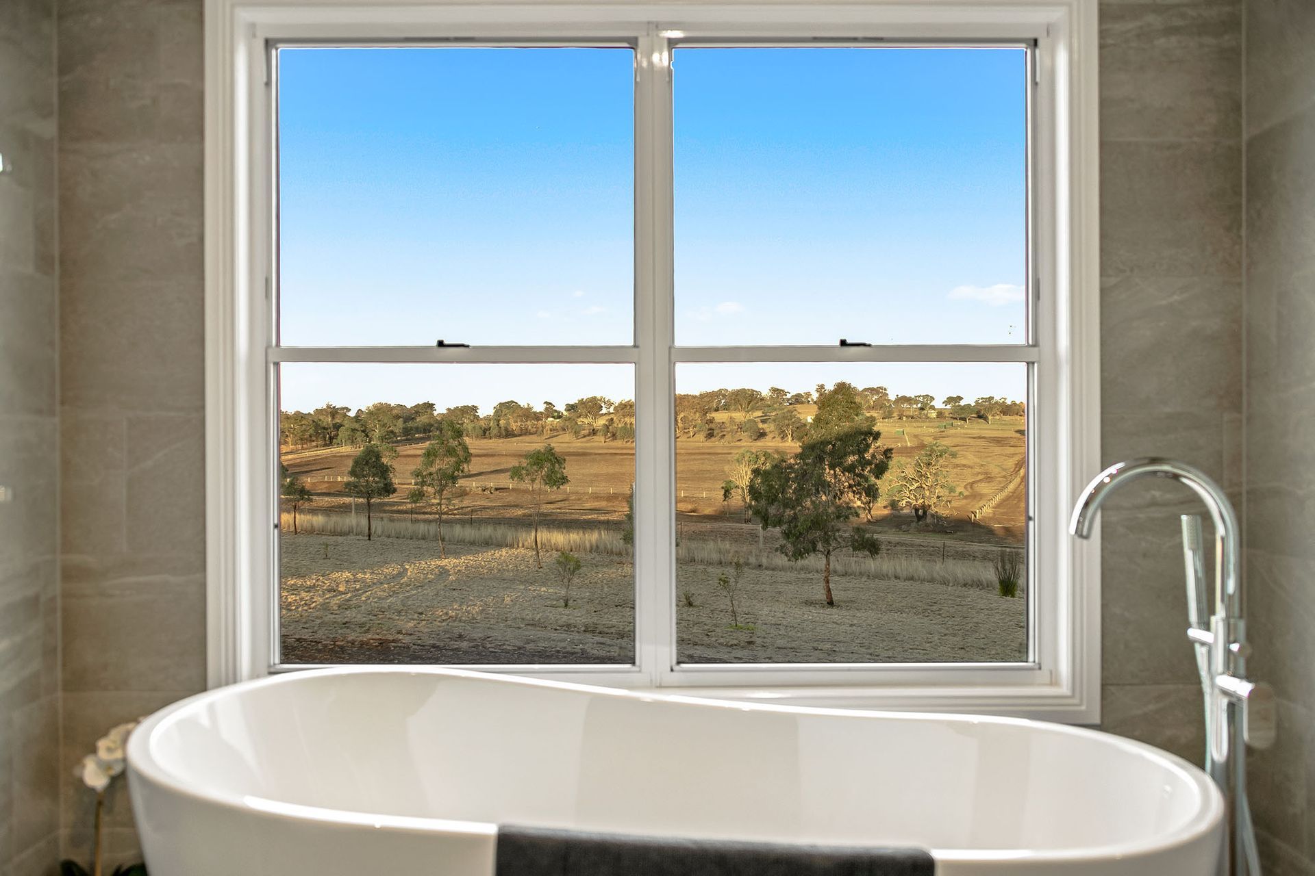 a bathroom with a bathtub and a window with a view of a field .