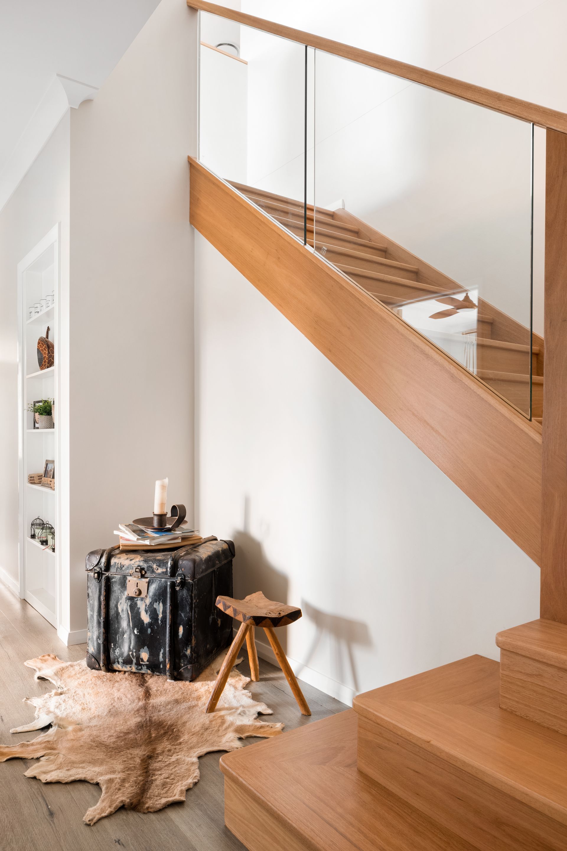 a wooden staircase with a glass railing in a hallway