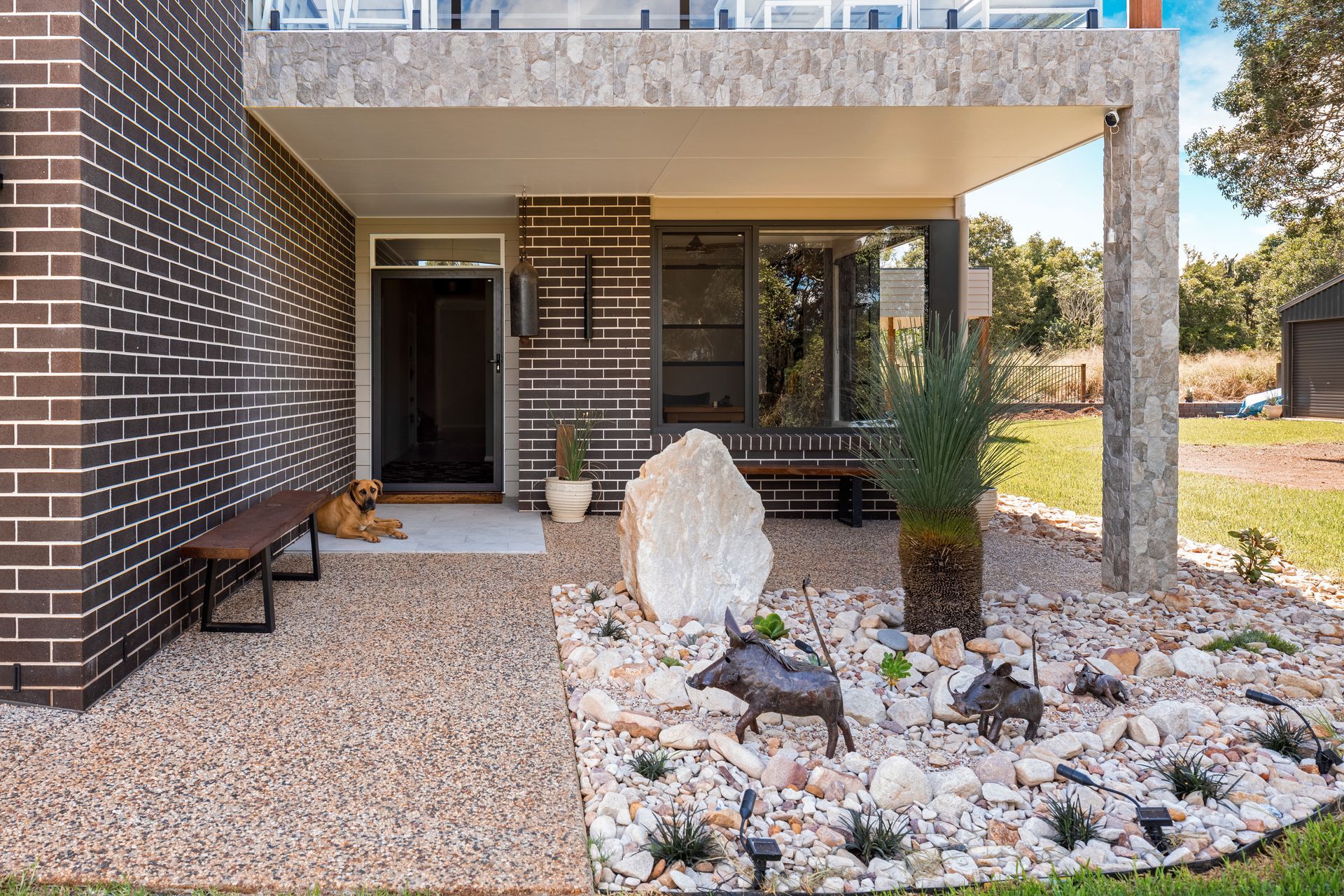 there is a large rock in the middle of the yard in front of the house .