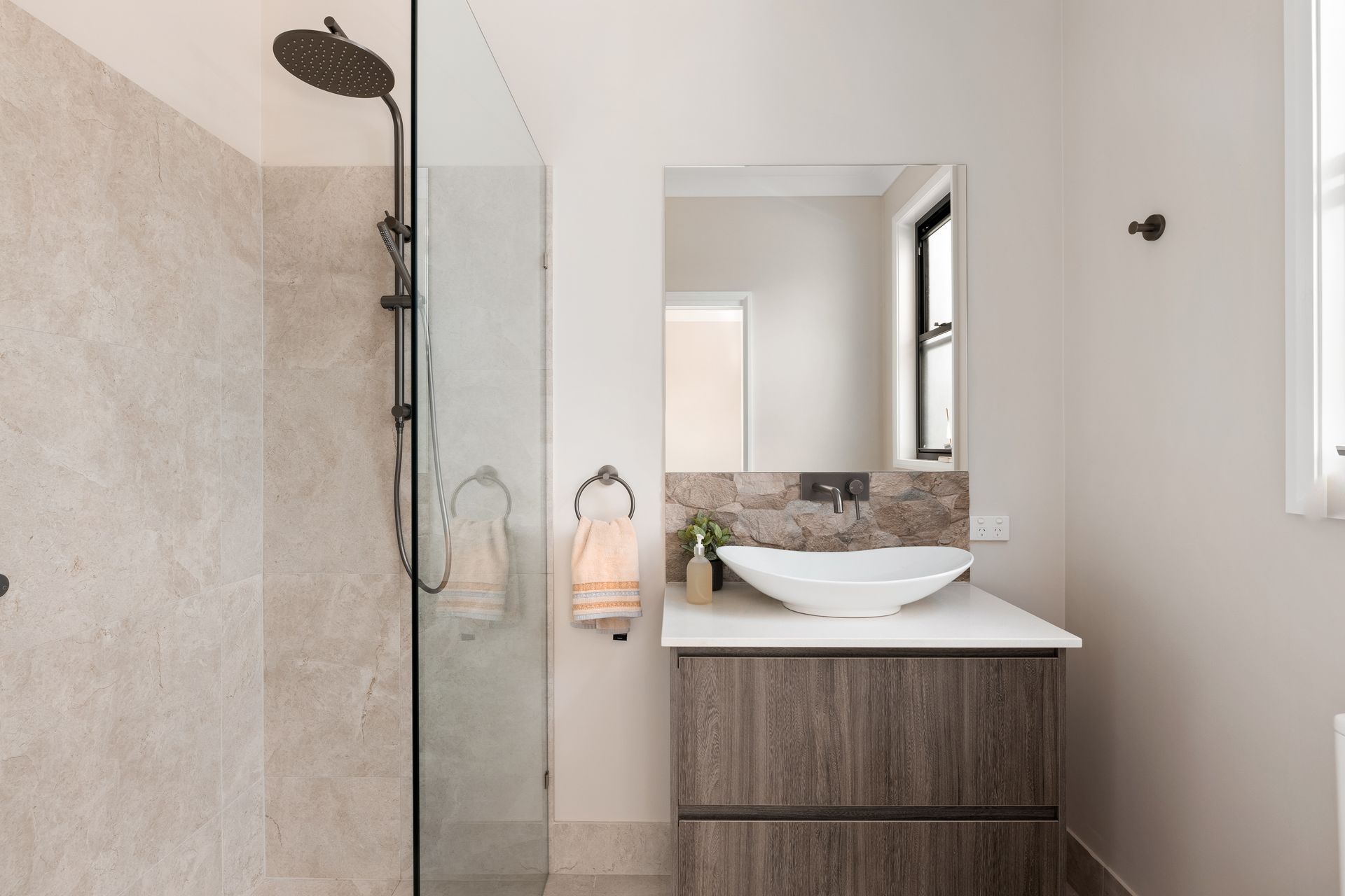a bathroom with a sink , shower and mirror .