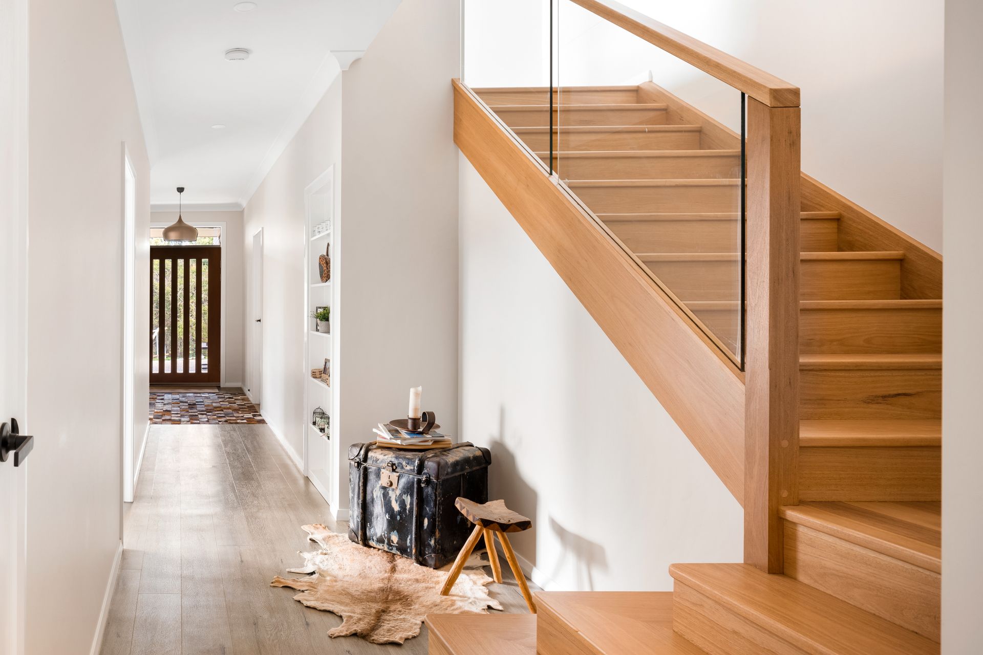 a hallway with a wooden staircase and a glass railing .