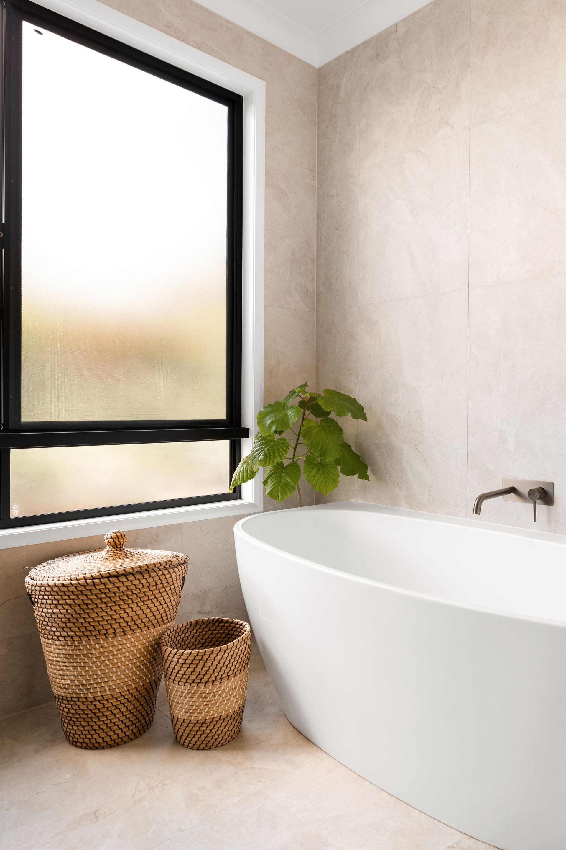 a bathroom with a bathtub , two baskets and a window .