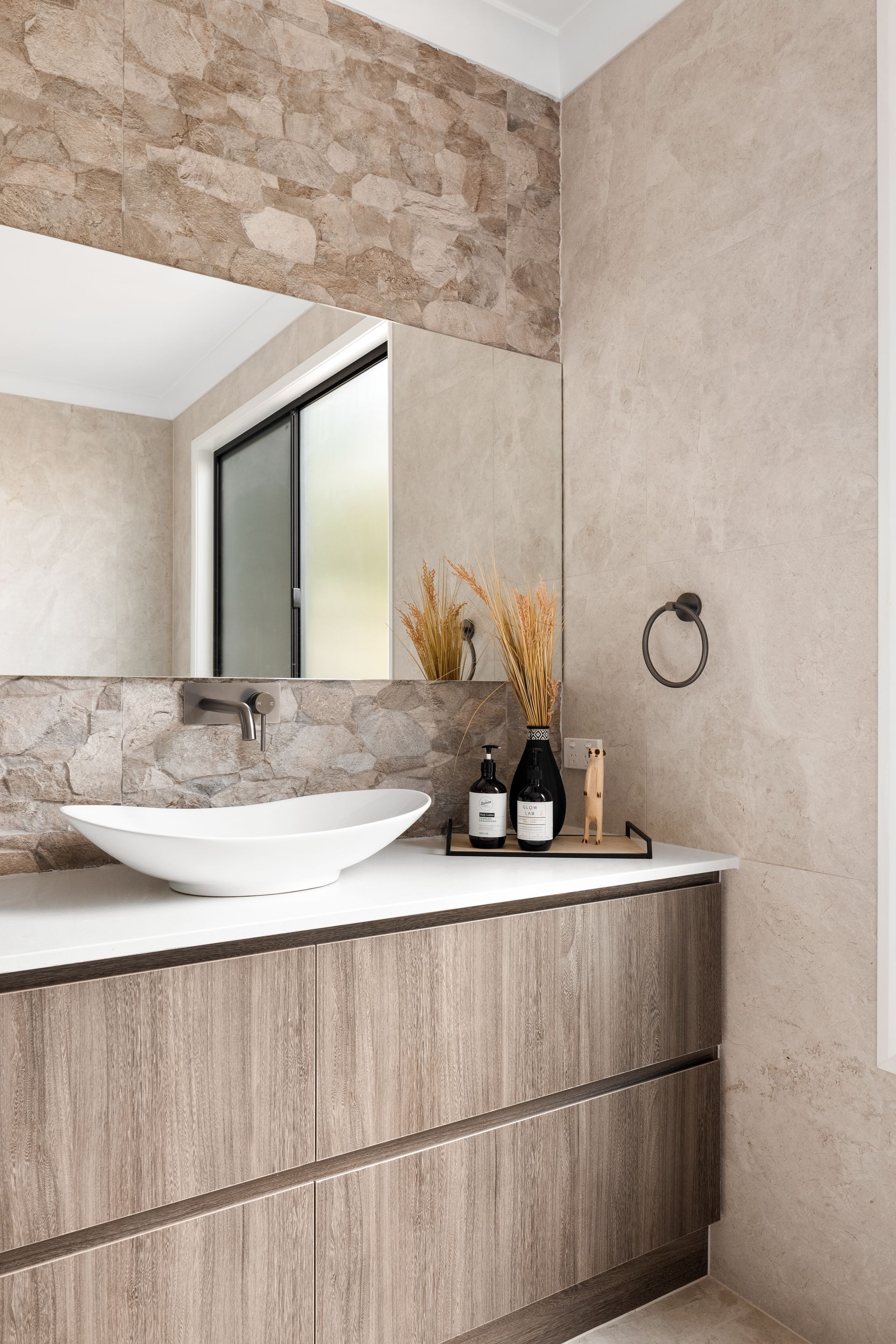 a bathroom with a sink , mirror and wooden cabinets .