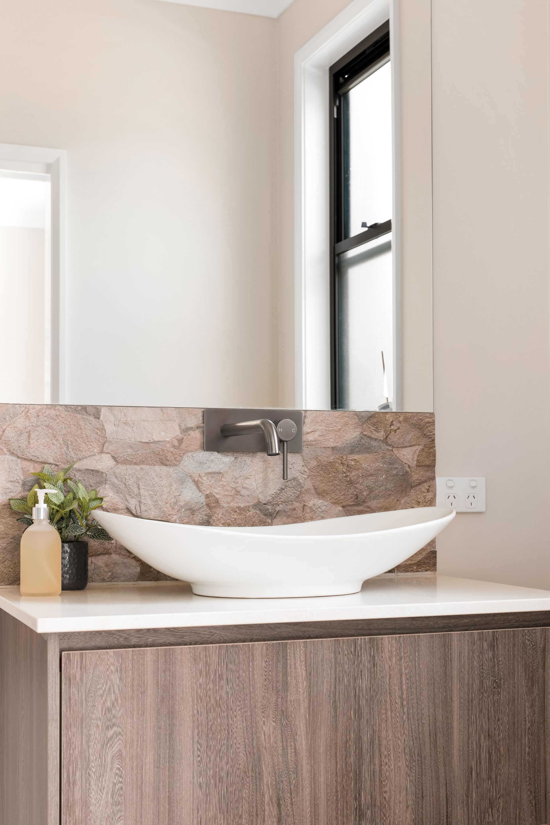 a bathroom with a sink , mirror and window .