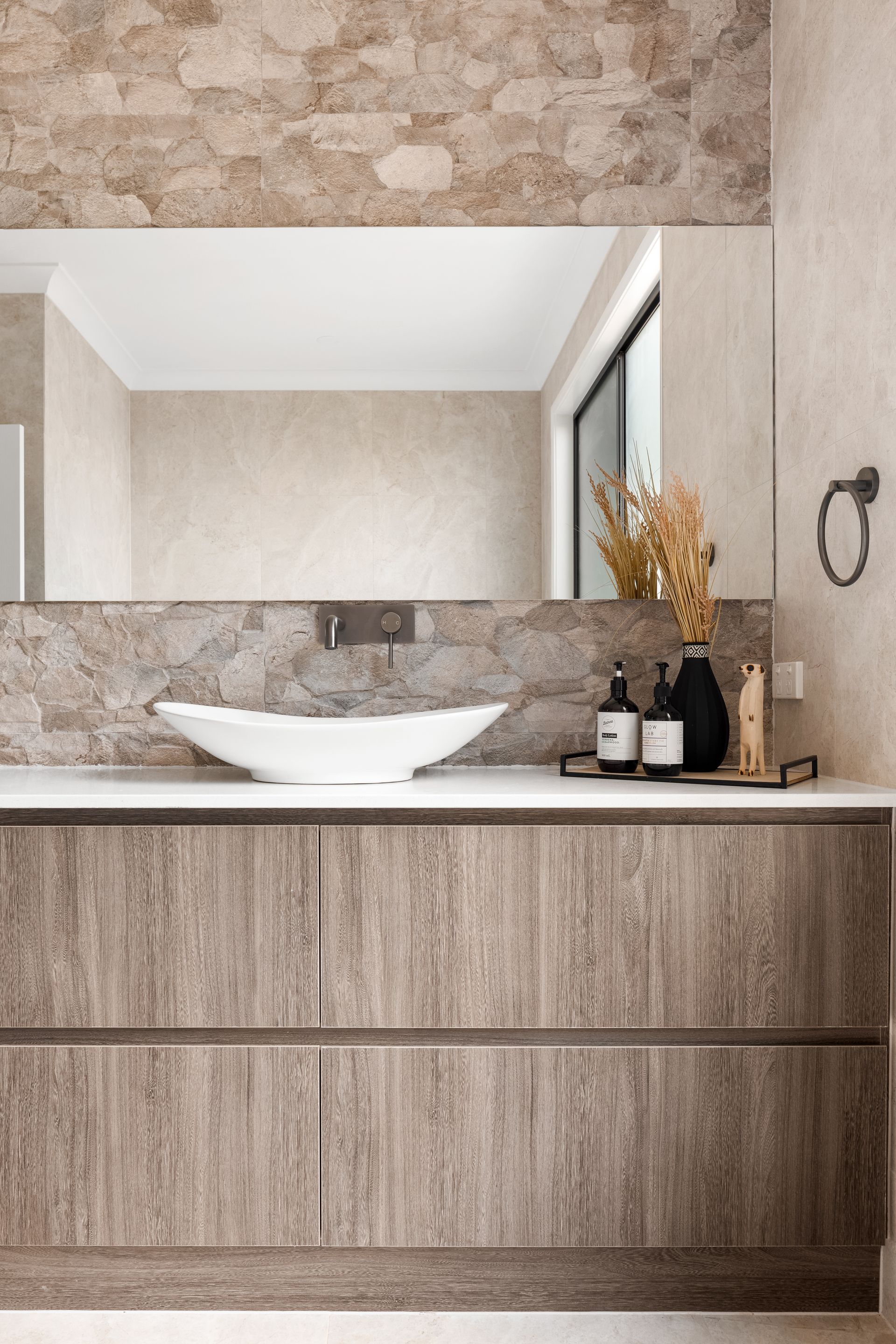 a bathroom with a sink , mirror , and wooden cabinets .