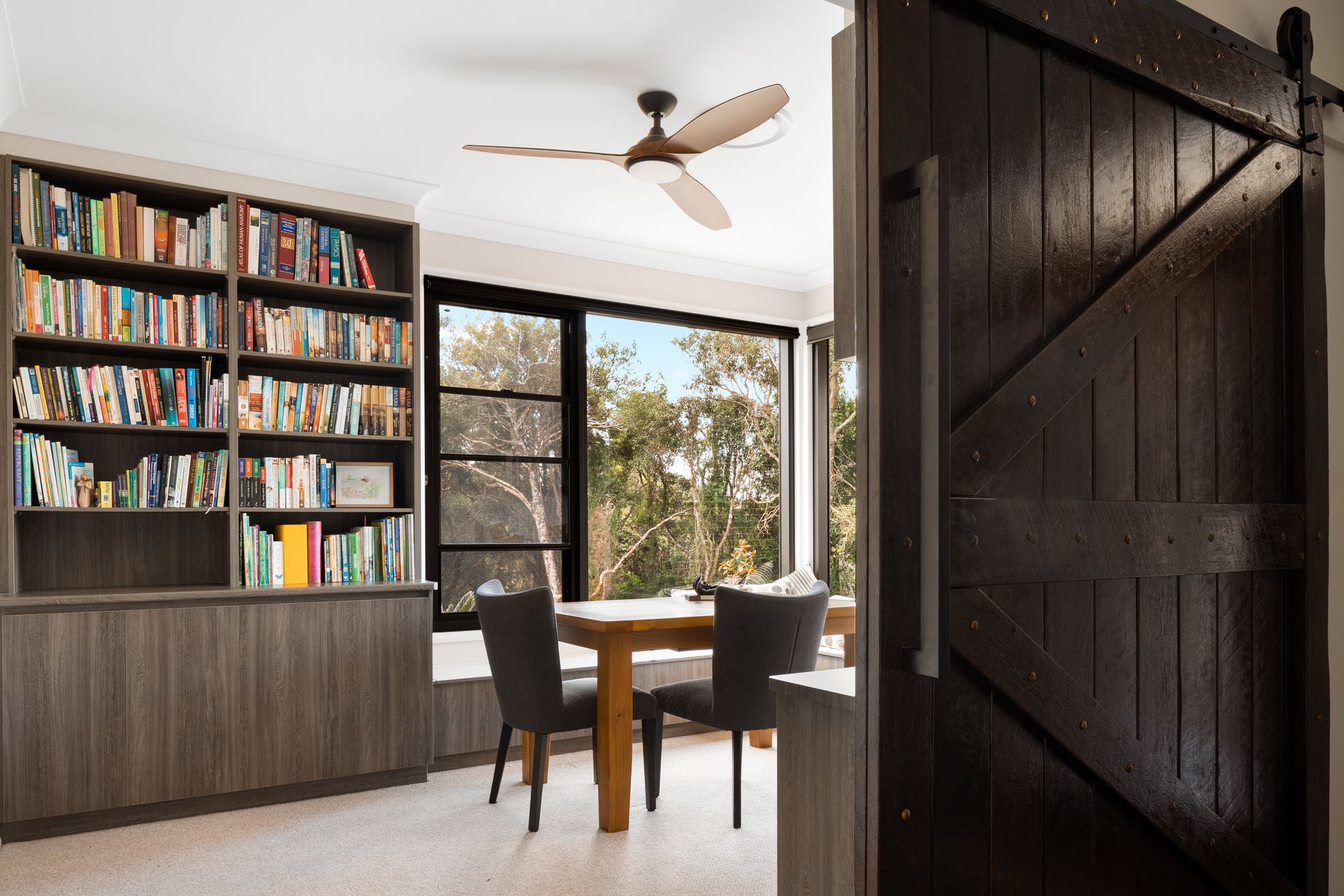 a living room with a table and chairs and a ceiling fan .