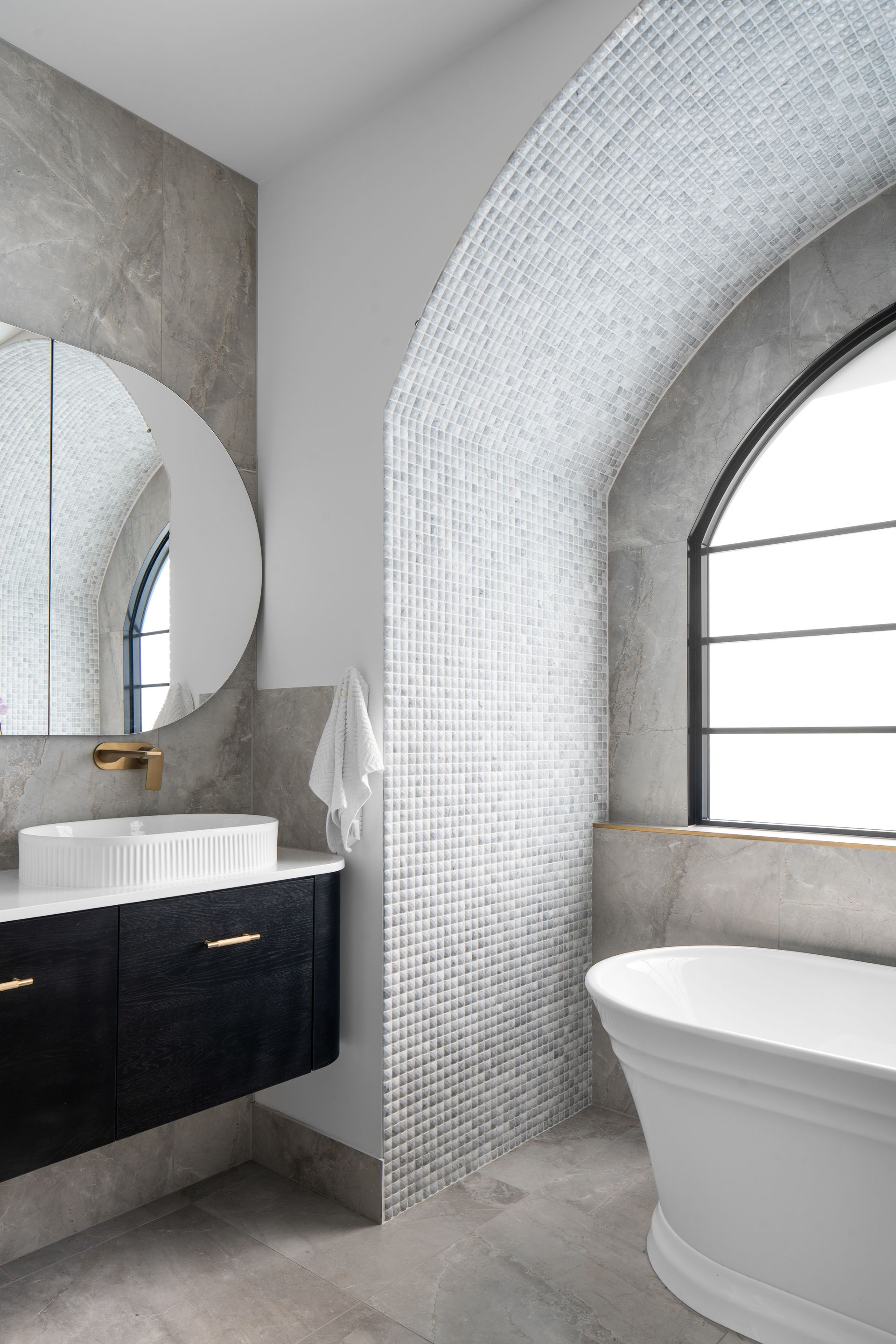 a bathroom with a tub , sink , mirror and window .