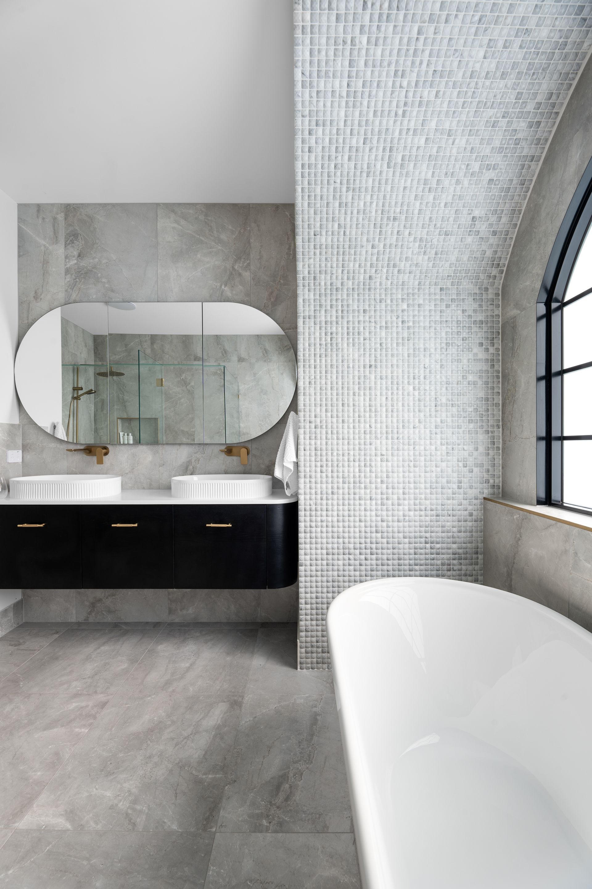 a bathroom with two sinks , a tub , a mirror and a window .