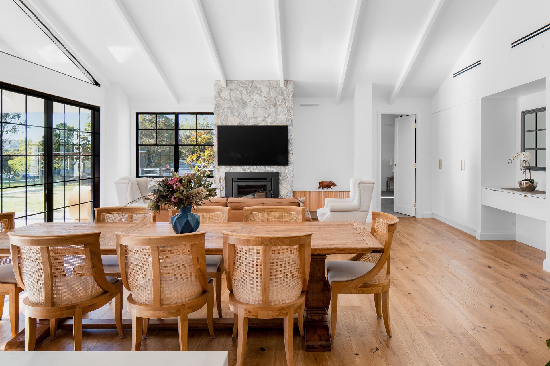 a dining room with a wooden table and chairs and a flat screen tv .