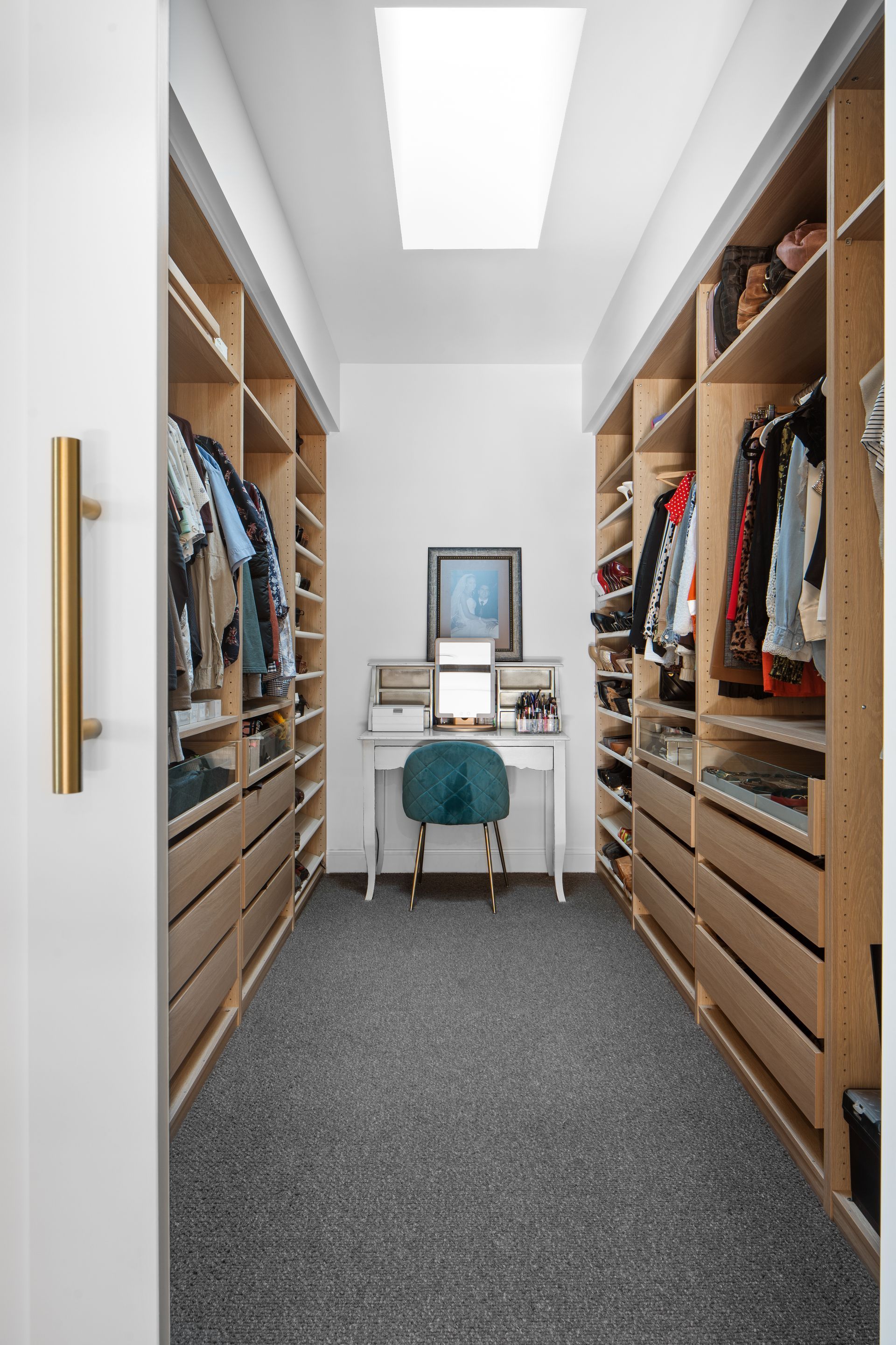 a walk in closet with lots of shelves and drawers and a vanity .