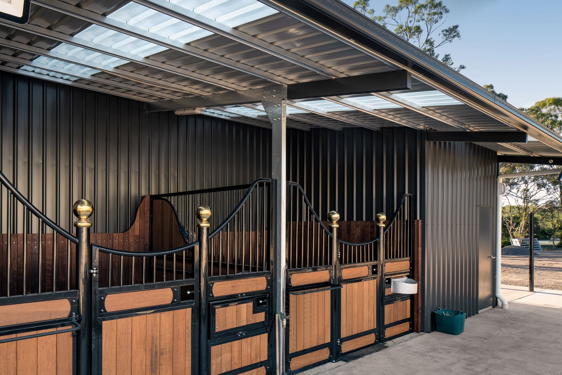 a horse stable with wooden doors and a black roof .