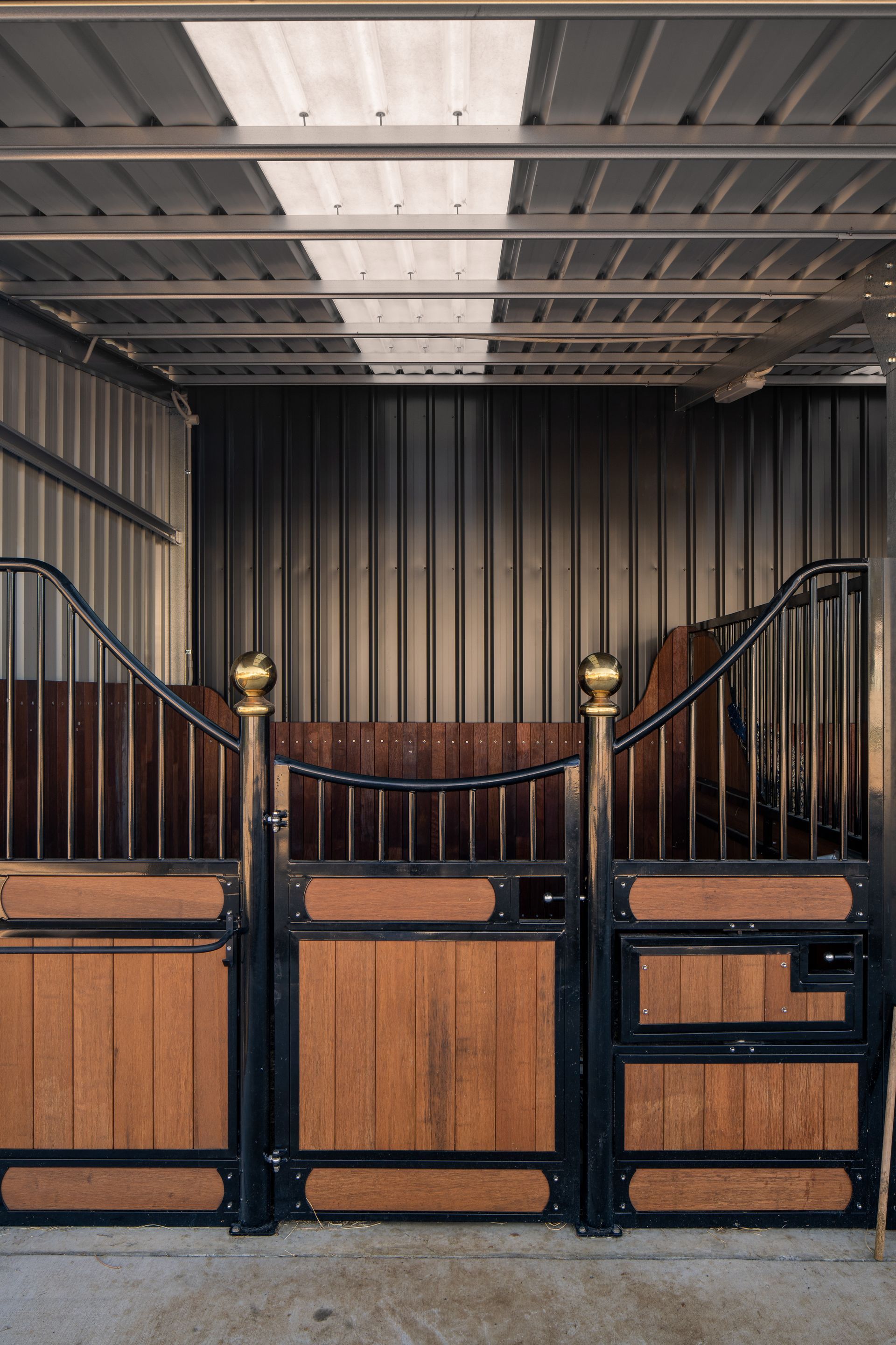 a horse stable with wooden gates and a metal wall .