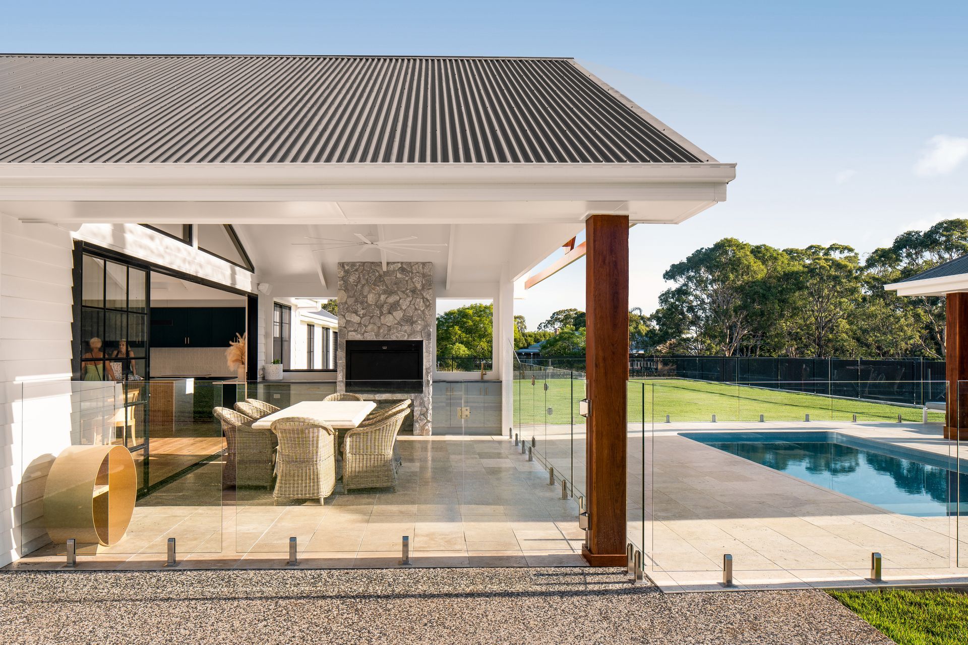 a house with a swimming pool and a patio area with a table and chairs .