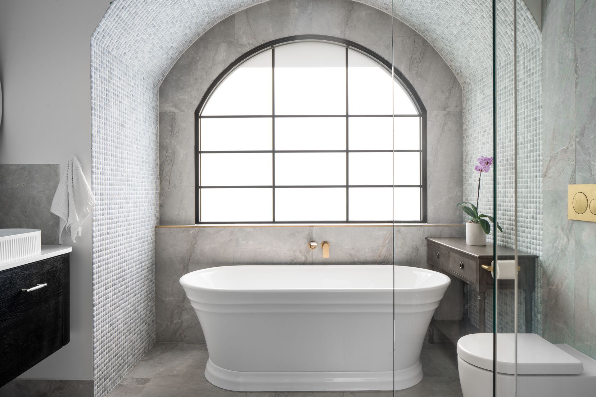 a bathroom with a tub , toilet , sink and window .