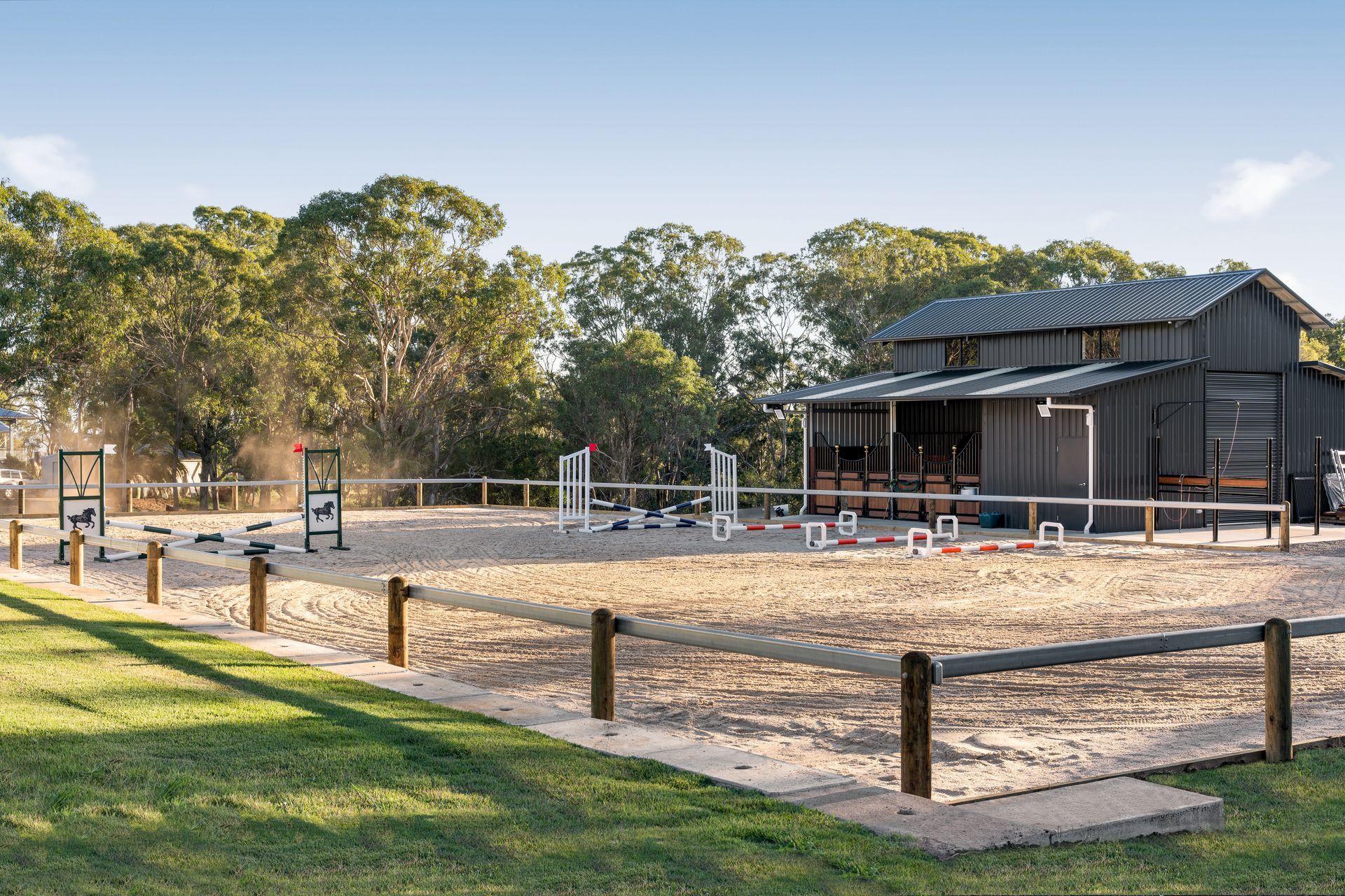 a horse riding arena with a fence and a barn in the background .