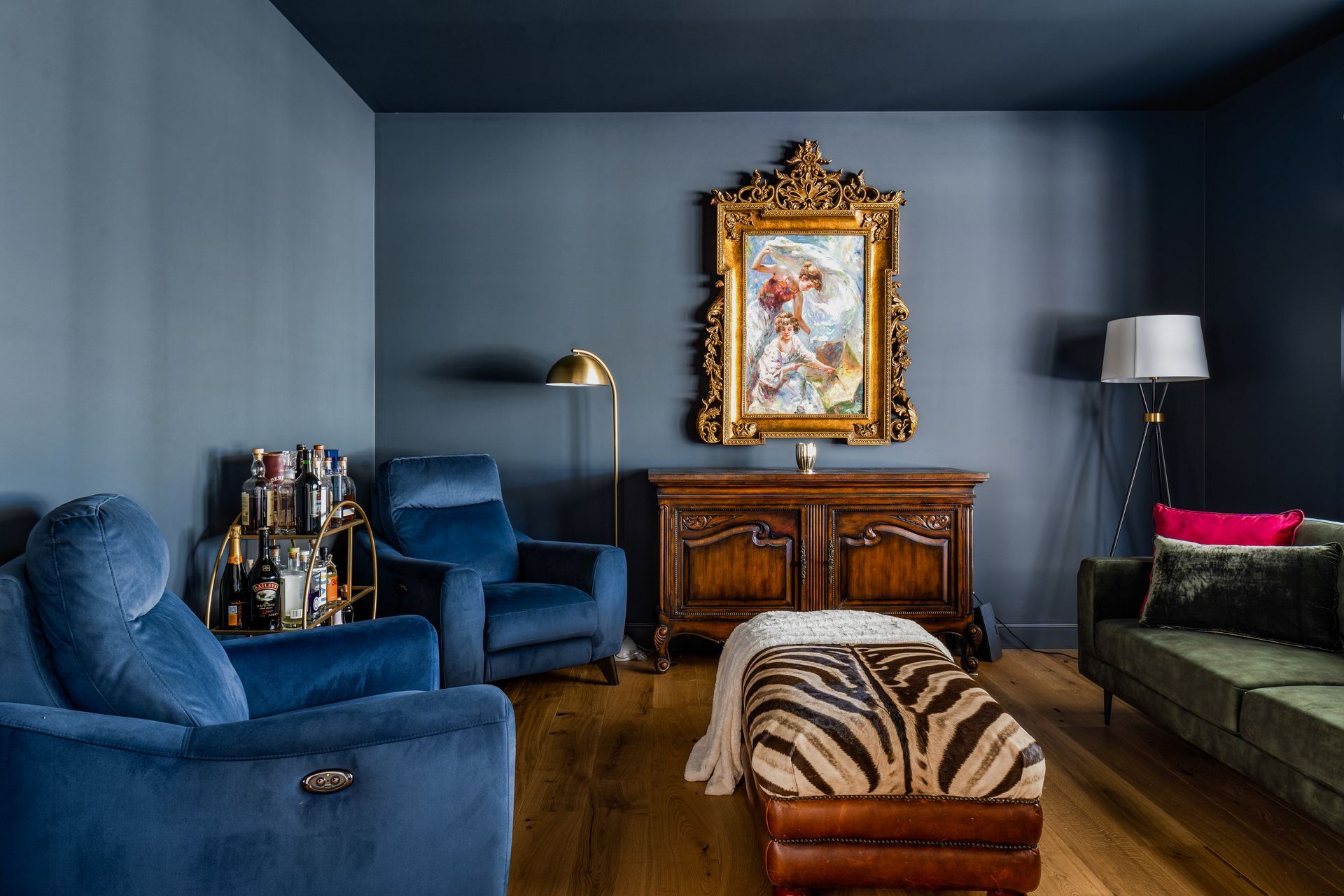 a living room with blue walls , blue chairs , a zebra print ottoman and a painting on the wall .