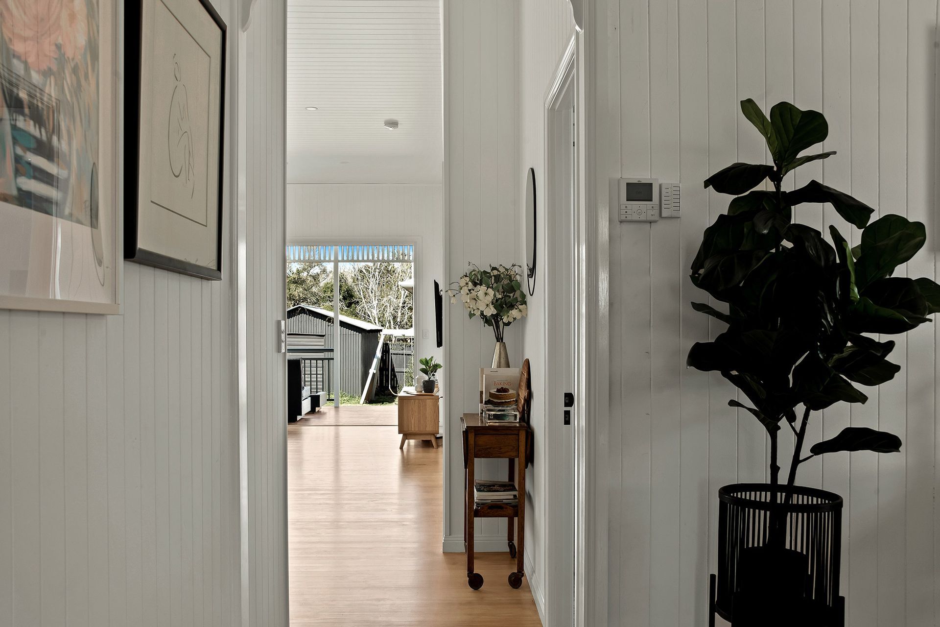 a hallway in a house with a potted plant and a table .