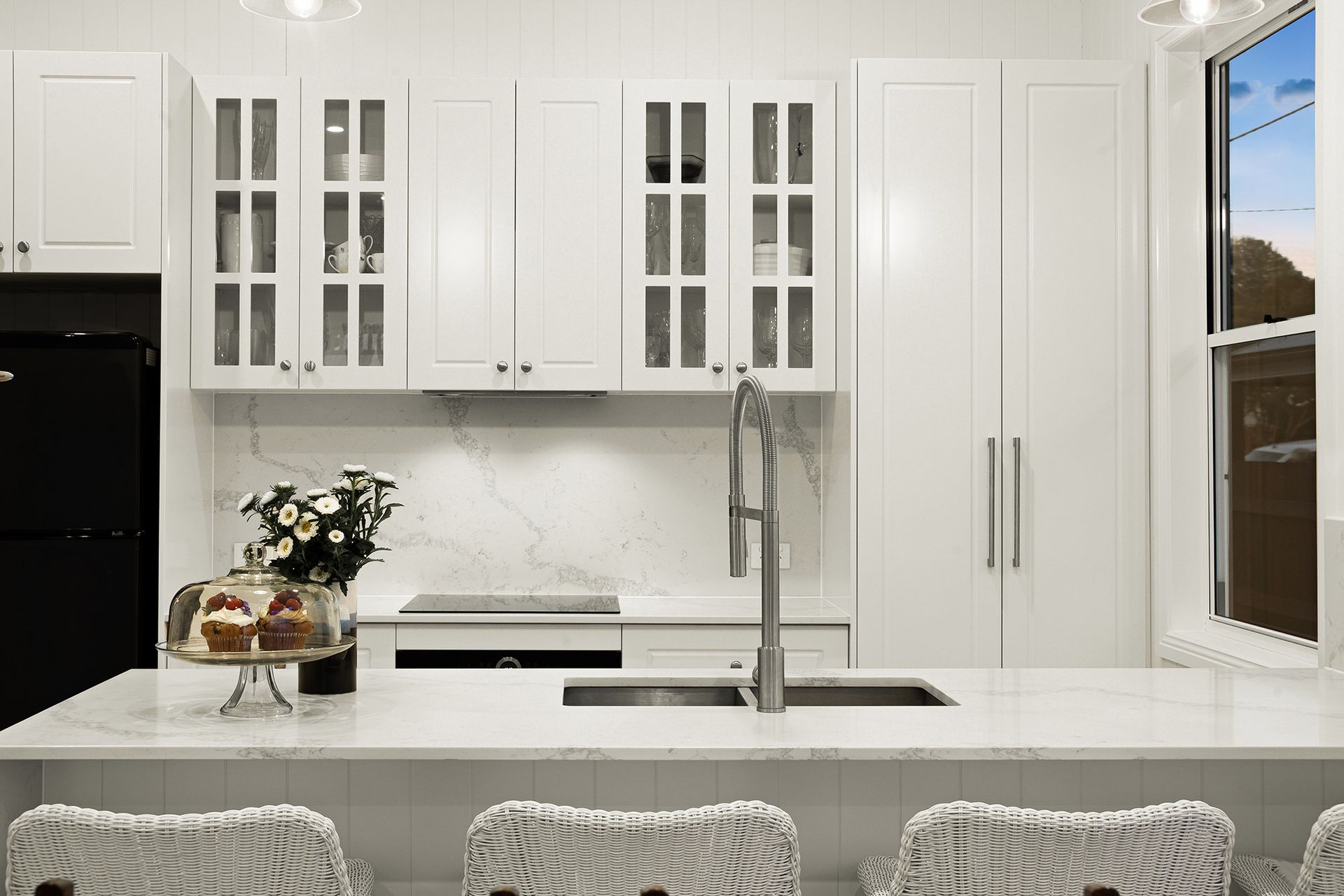 a kitchen with white cabinets , a sink , a stove and a window .