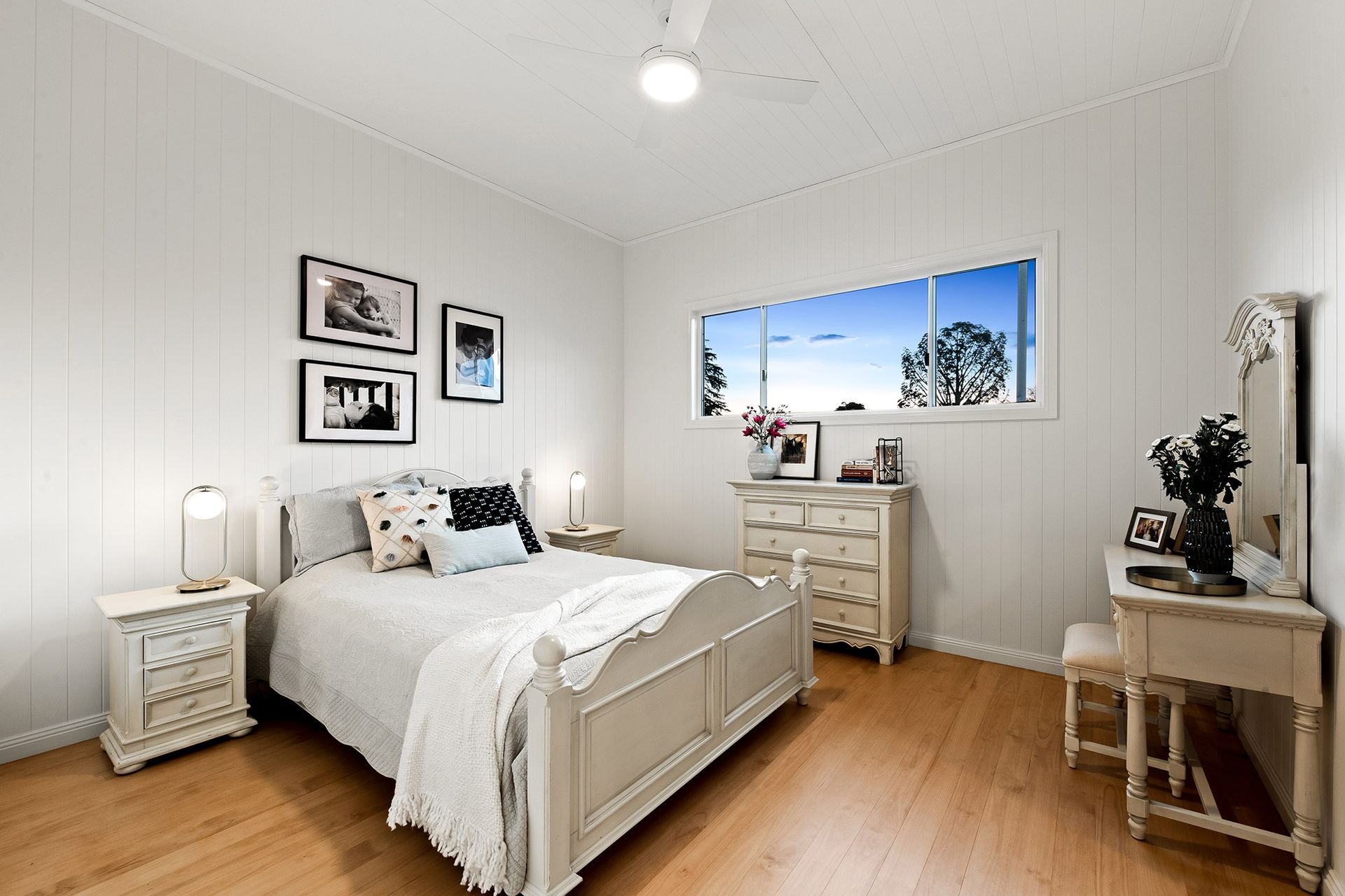 a bedroom with a bed , dresser , nightstand , mirror and window .