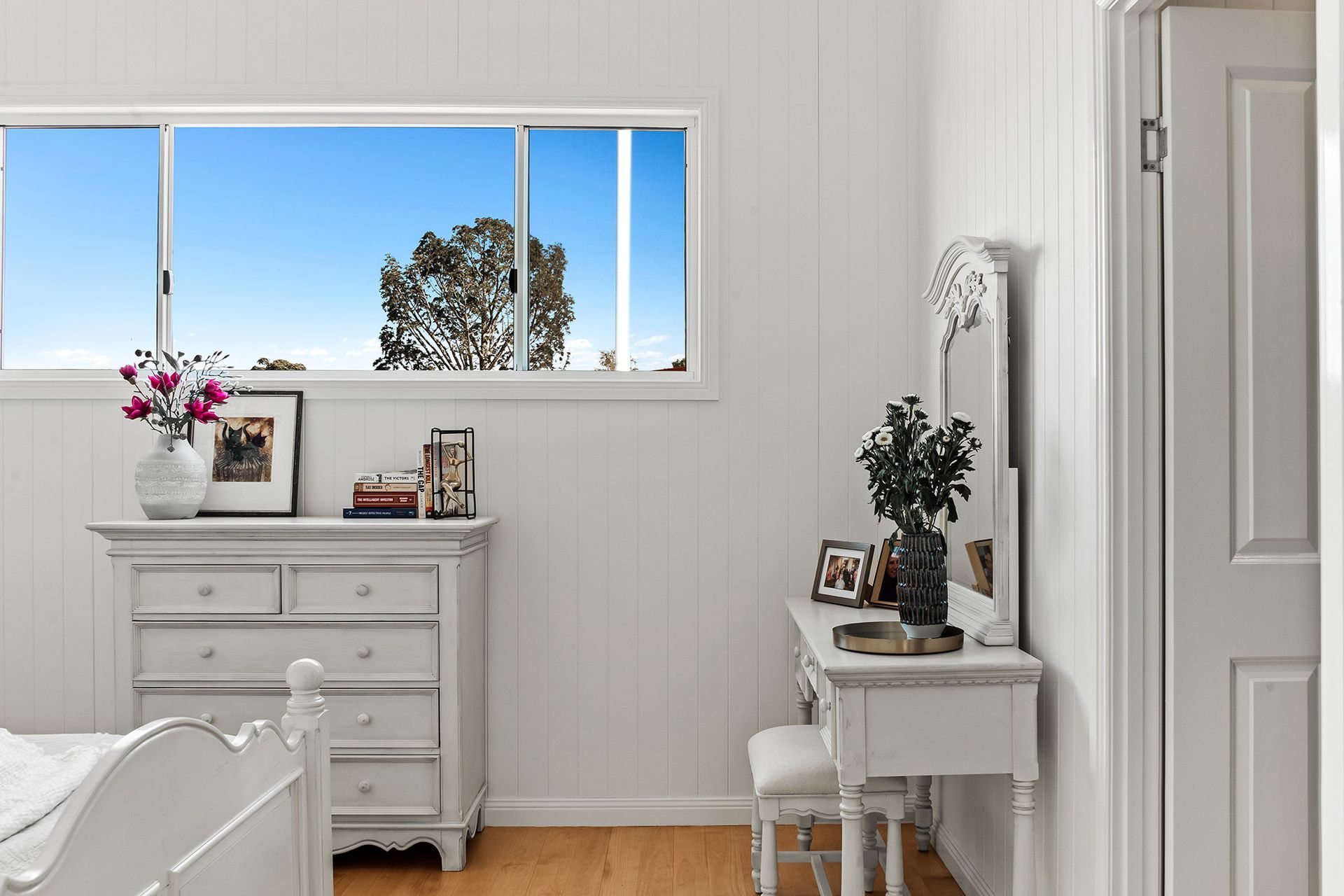 a bedroom with a bed , dresser , mirror and window .