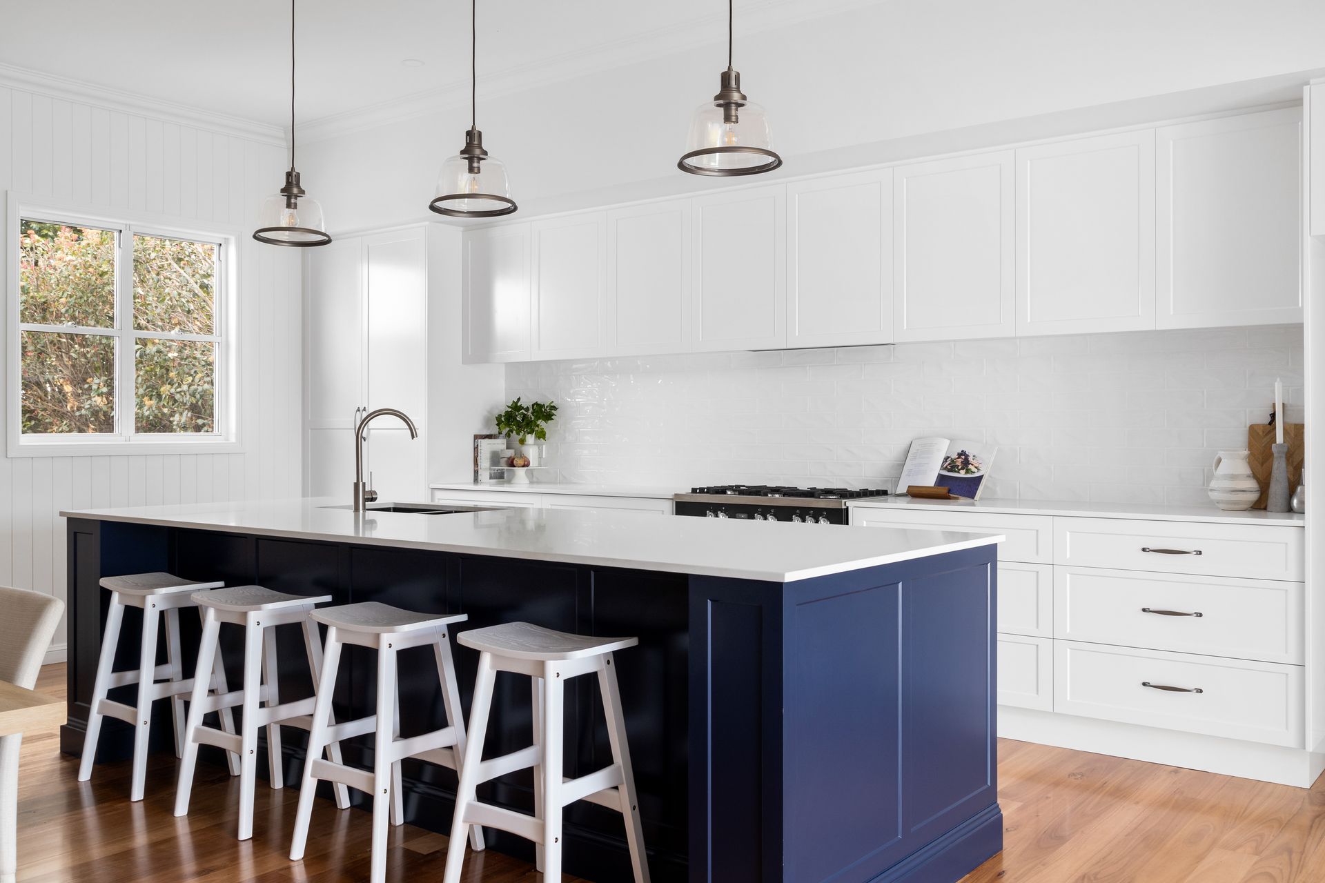 a kitchen with a blue island and white stools .
