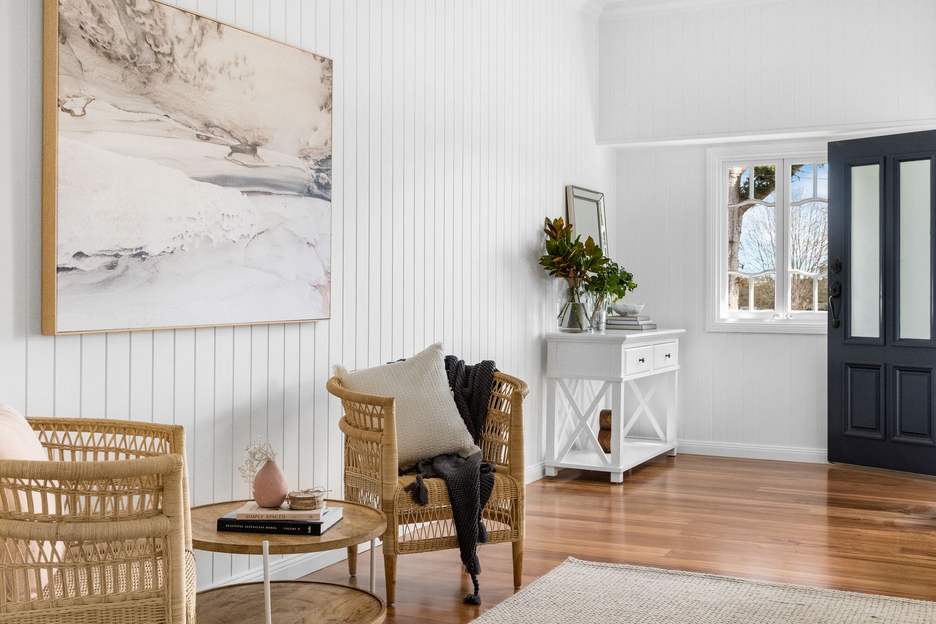 a living room with a wicker chair and a painting on the wall .
