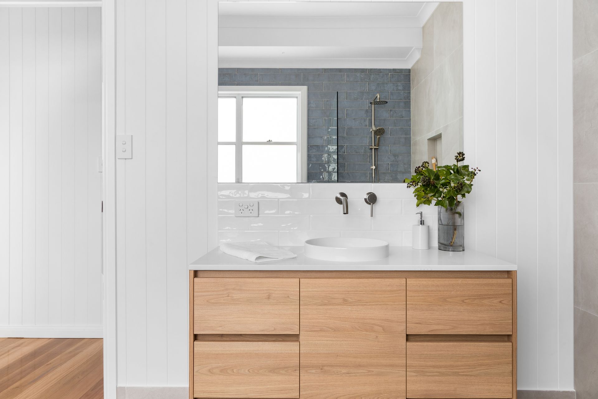 a bathroom with a wooden vanity , sink and mirror .