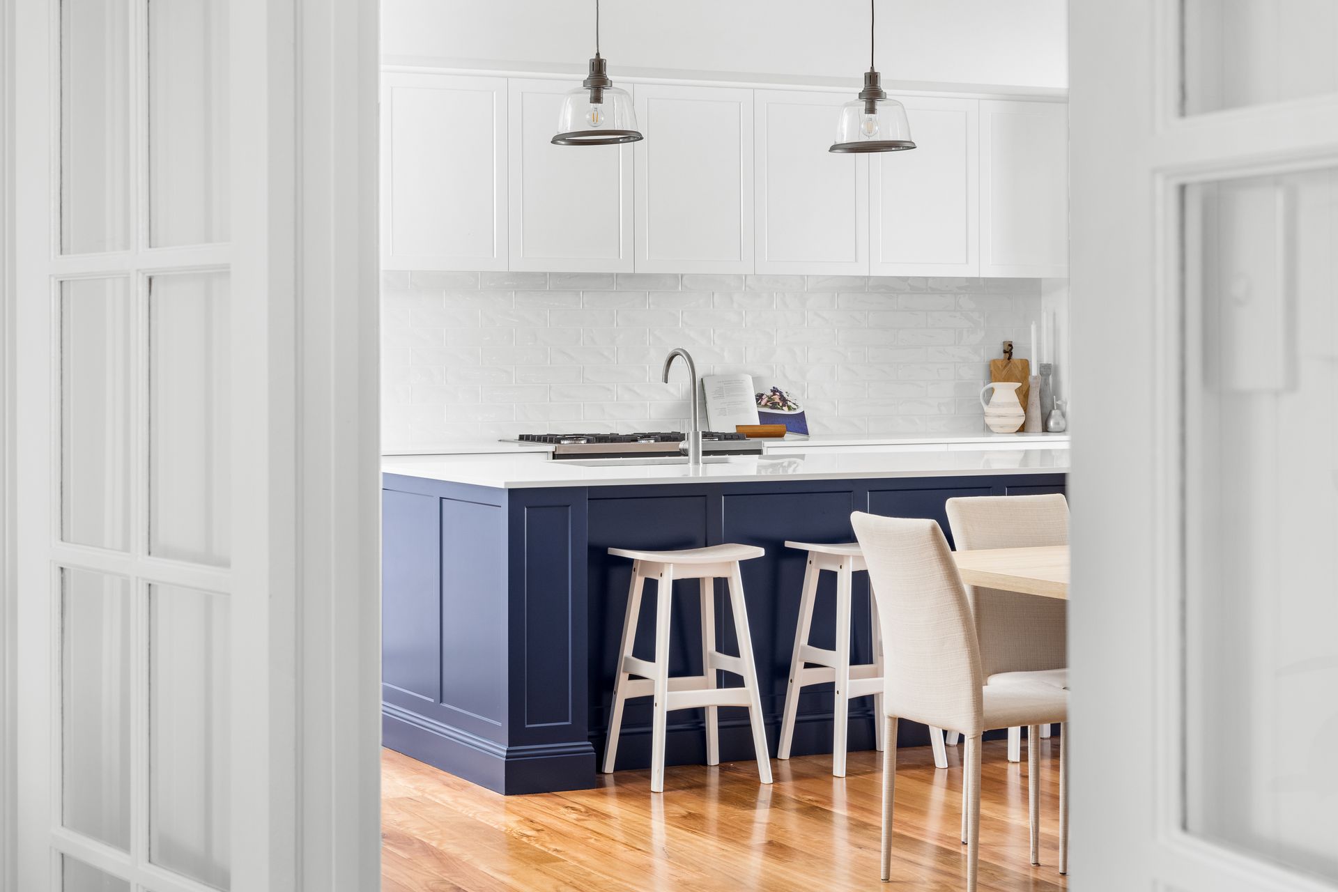 a kitchen with blue cabinets and white counter tops and stools .