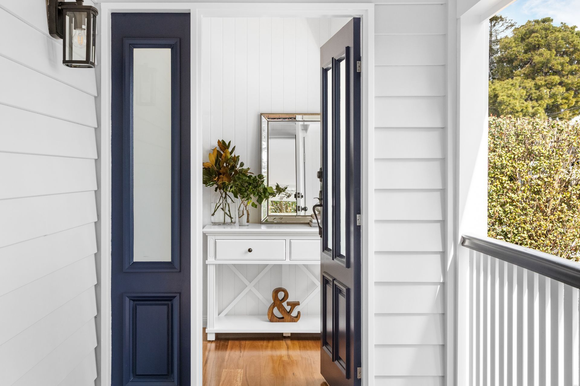 a white house with a blue door and a mirror on the porch .