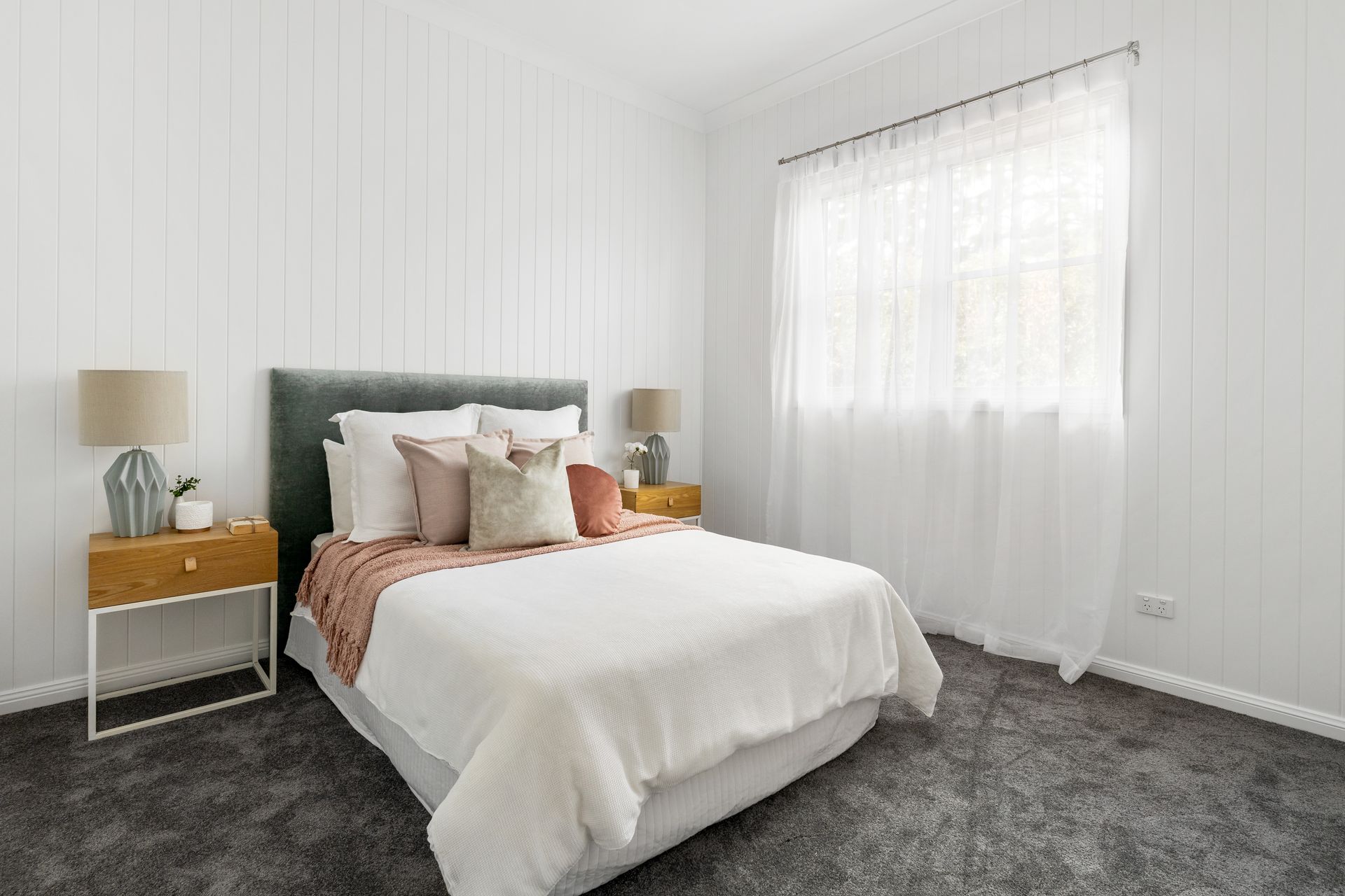 a bedroom with a bed , nightstand , lamps and a window .