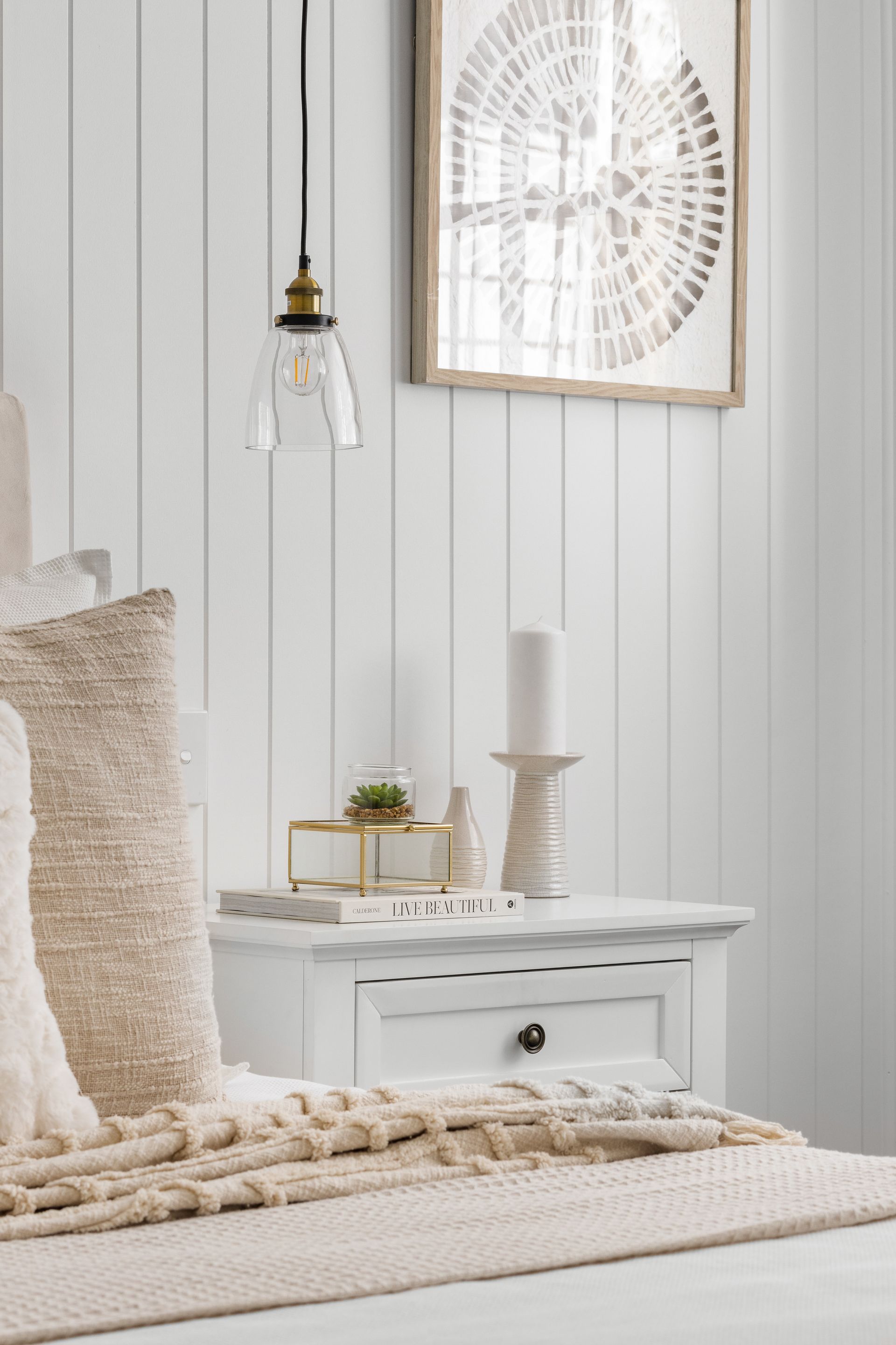 a bedroom with a bed , nightstand , candles and a picture on the wall .