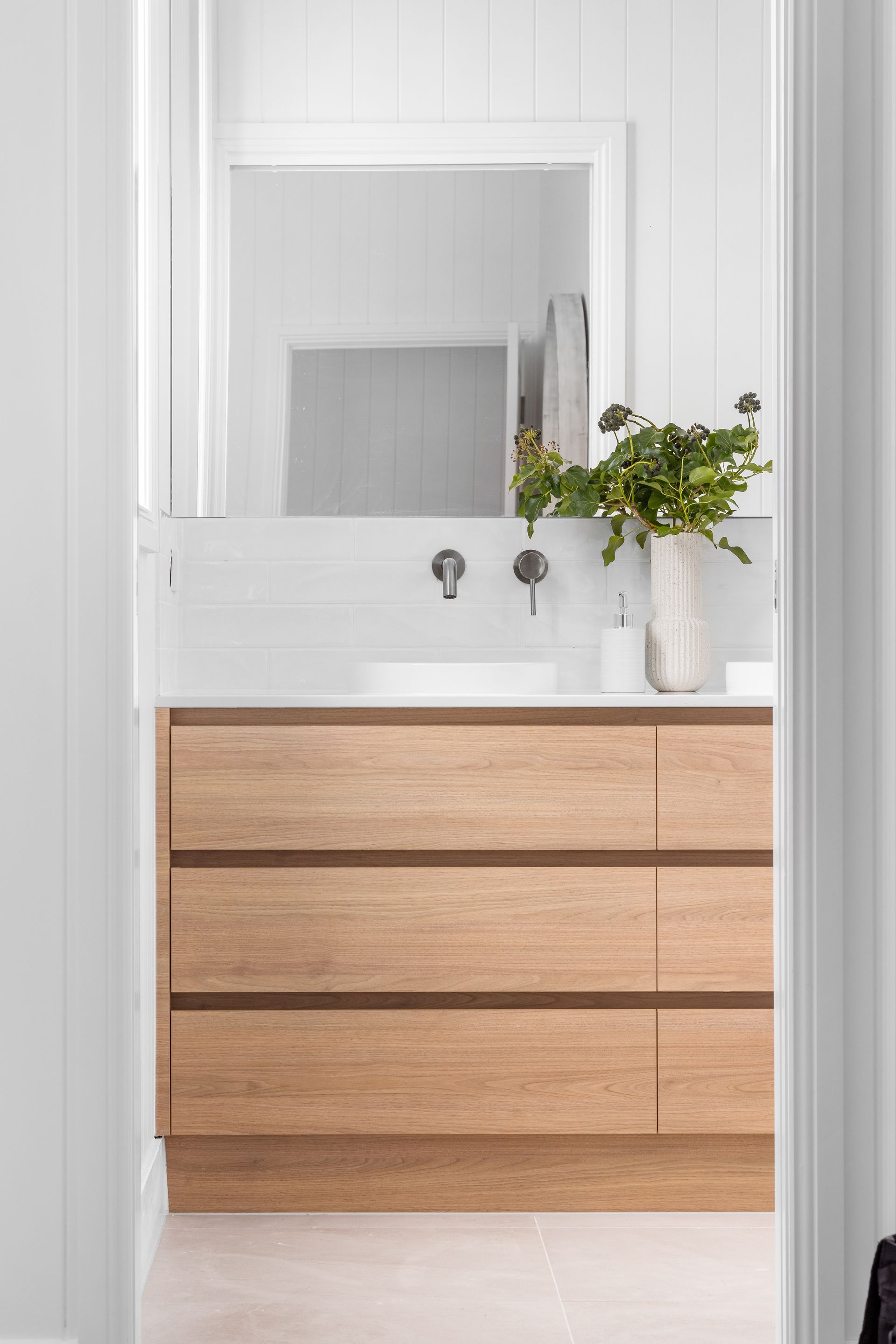 a bathroom with a wooden vanity , sink , mirror and drawers .