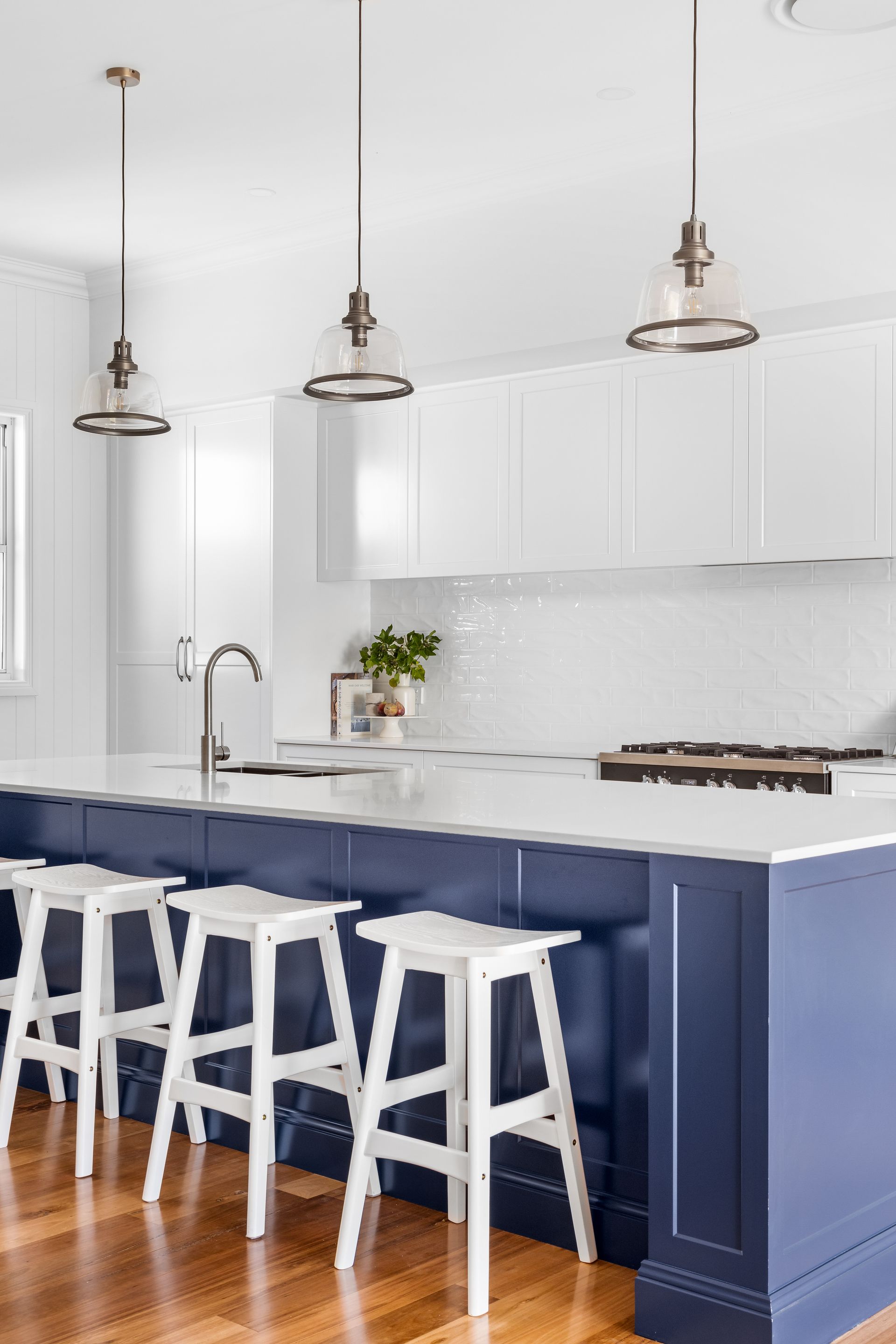 a kitchen with blue cabinets and white counter tops and stools .