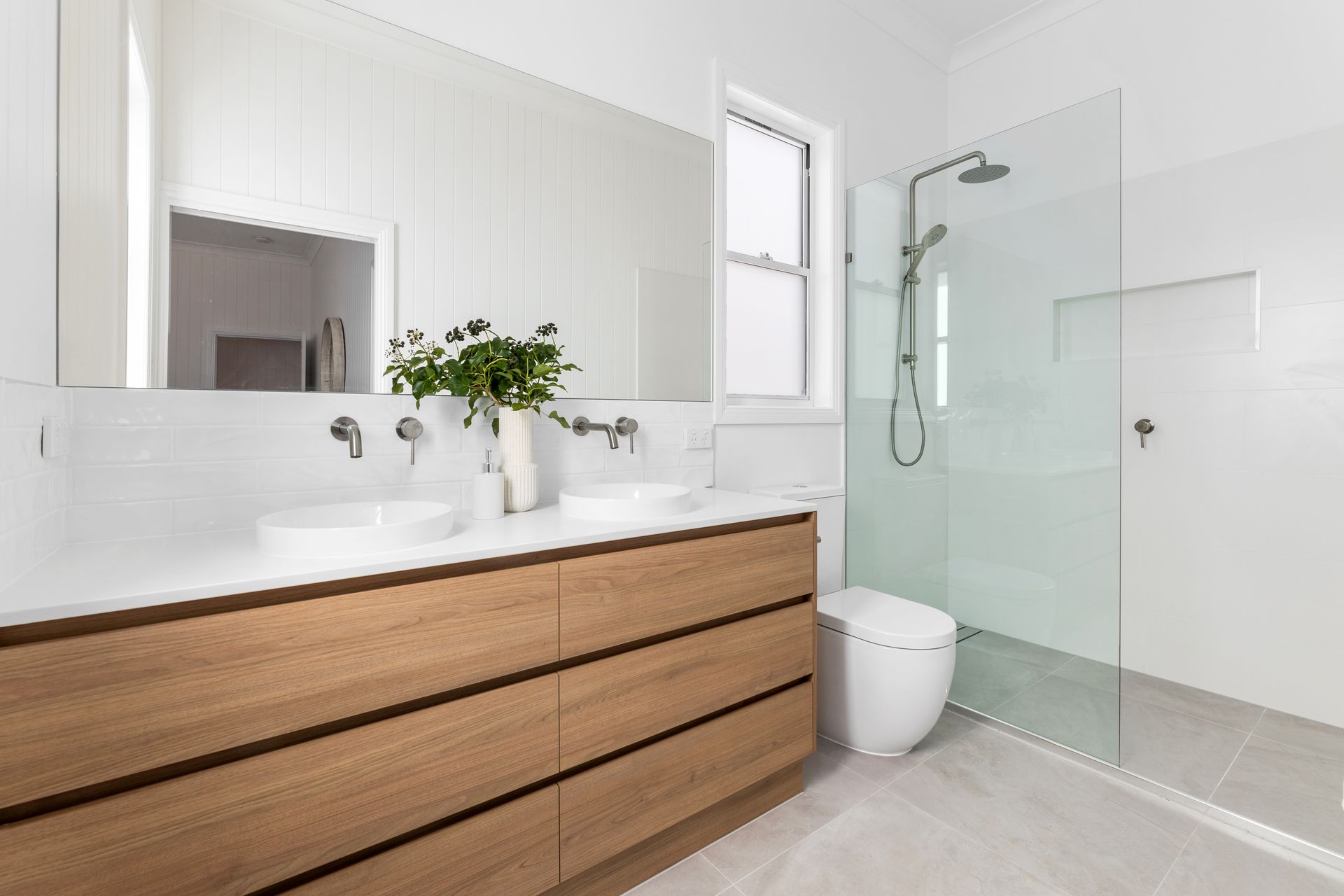 a bathroom with two sinks , a toilet , and a walk in shower .